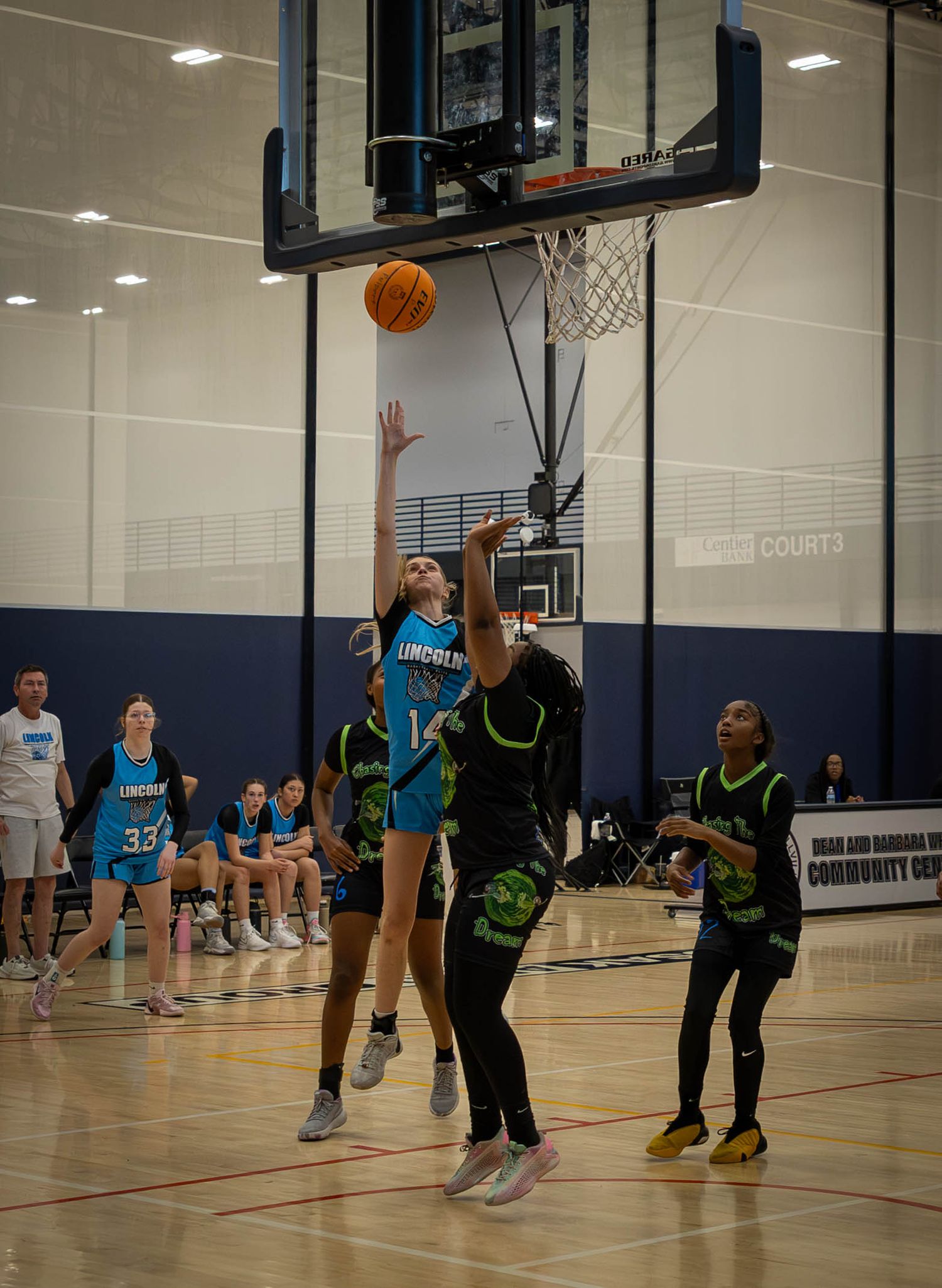 Basketball players engage in a competitive game on an indoor court with players in blue and black uniforms.
