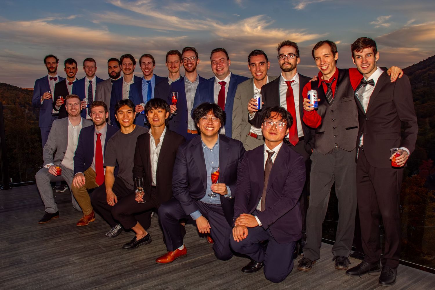 Large group of well-dressed men posing together at an outdoor evening celebration event.