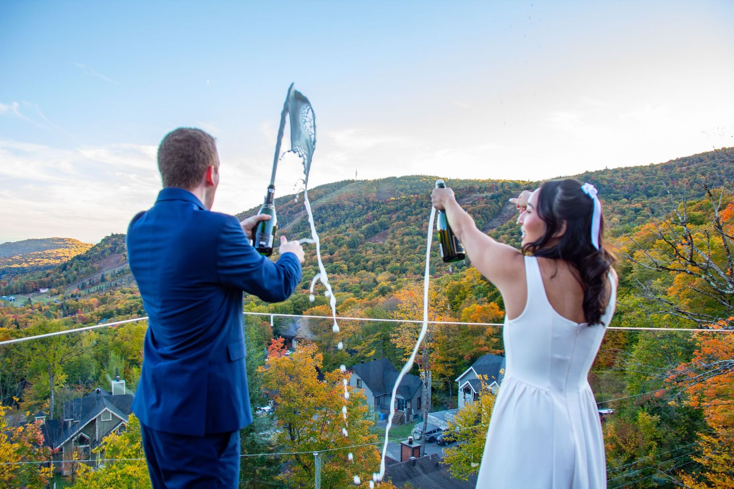 Bride and groom celebrating on mountain terrace with butterfly net against autumn hillside backdrop.