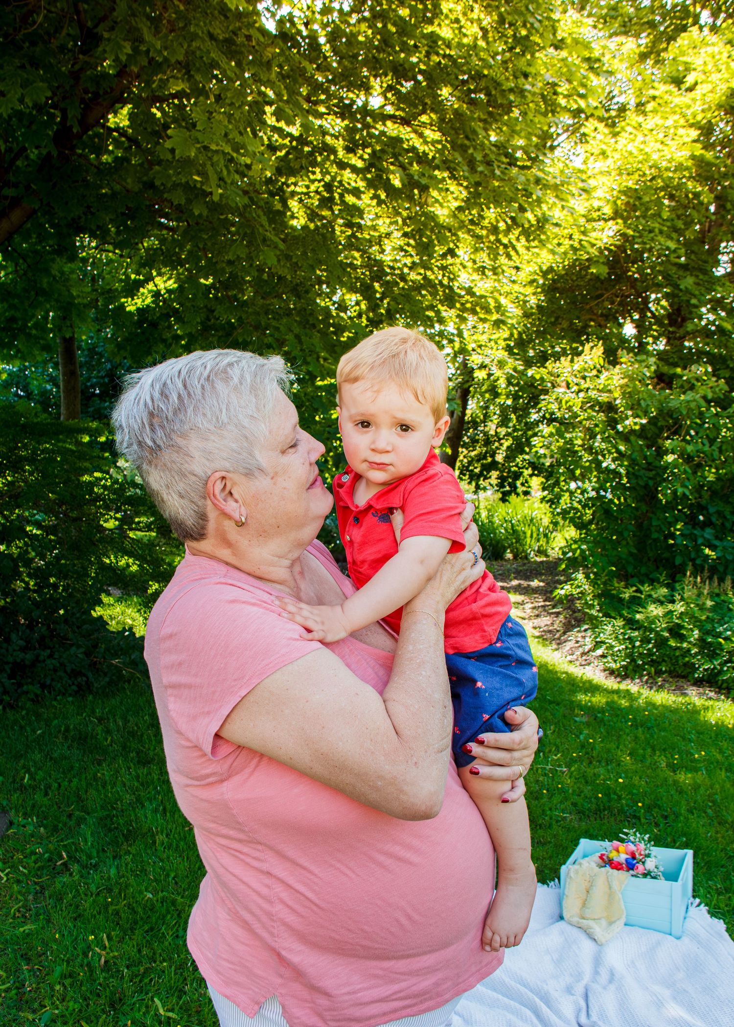 Grand-maman tenant son petit-fils dans ses bras lors d'une séance photo en plein air au Domaine Maizeret.