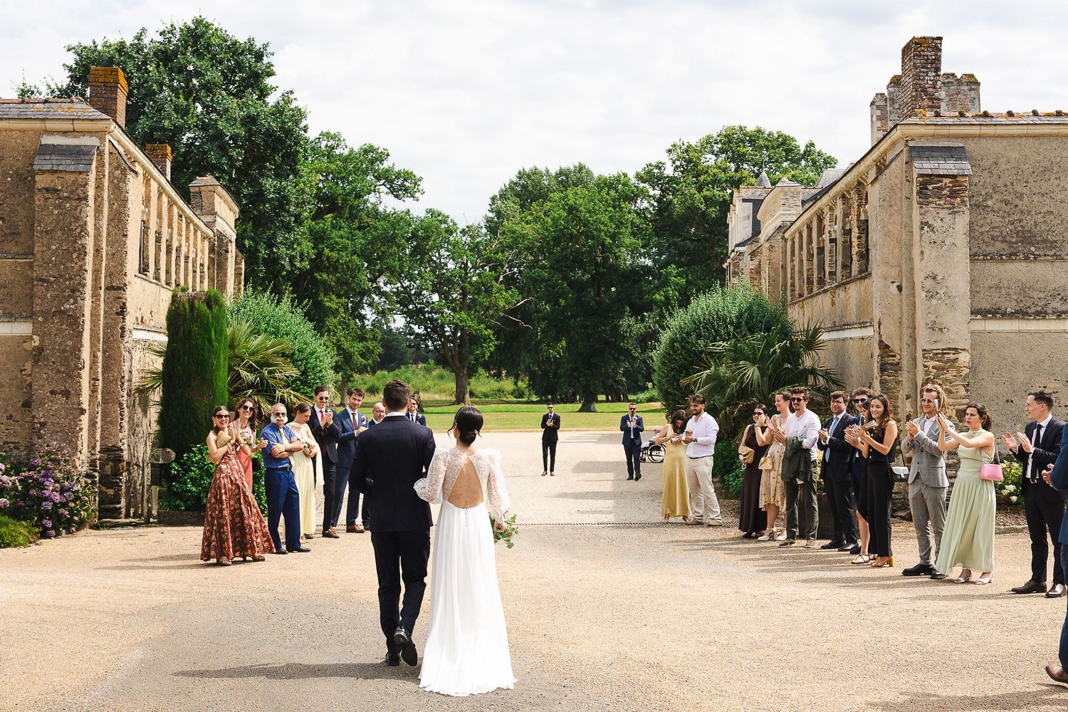 Bride and groom walk through cheering wedding guests at an elegant English countryside estate venue.