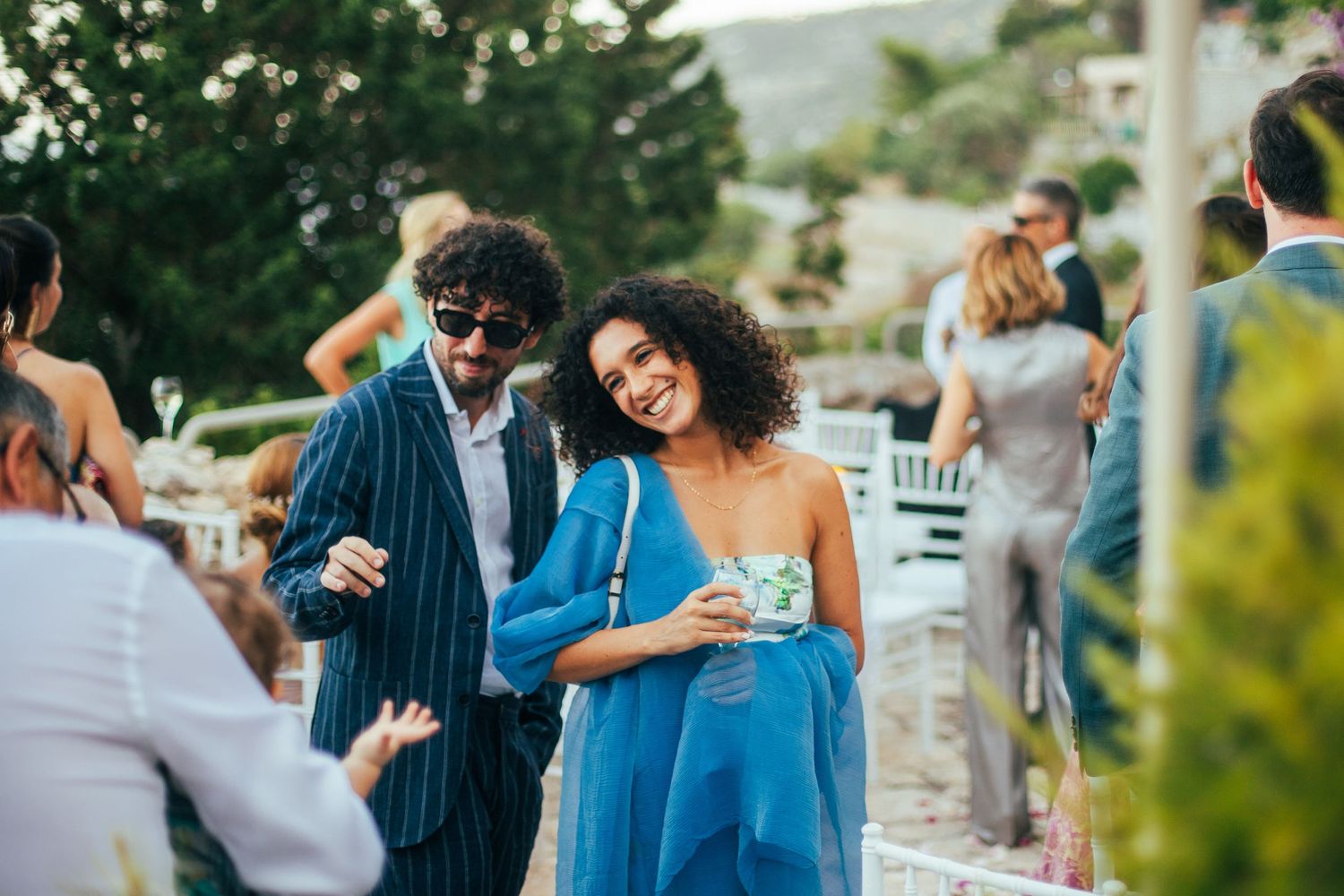 People celebrating at an outdoor event with drinks as guests mingle and socialize during golden hour.