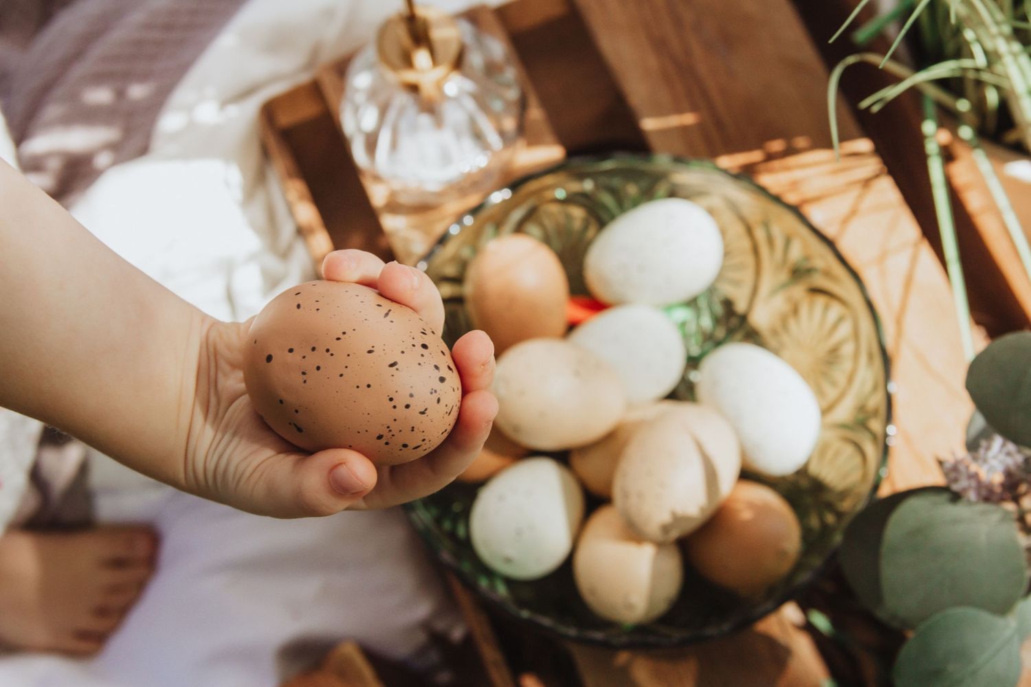 Collection of decorated Easter eggs in natural brown and white tones with greenery.