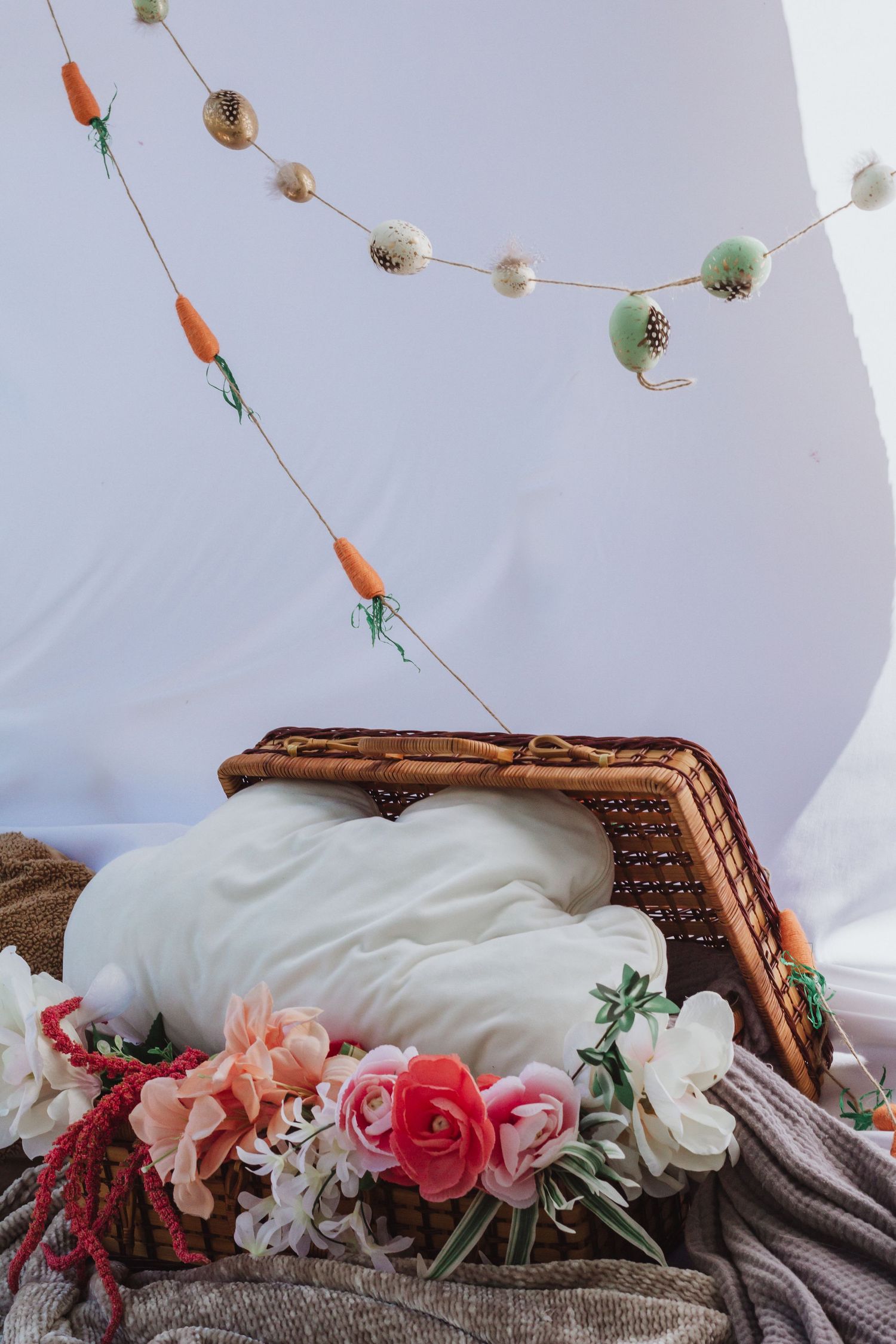Dreamy scene with hanging ornaments, flowers, and wooden frame against white backdrop.