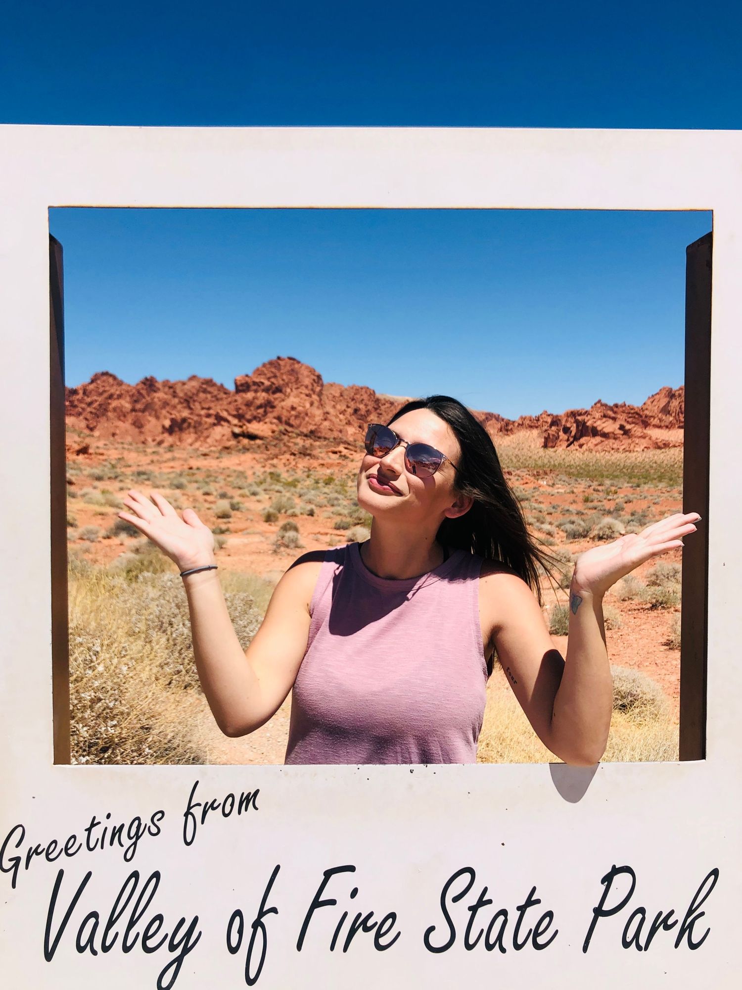 Visitor takes joyful photos at Valley of Fire State Park surrounded by desert landscape.