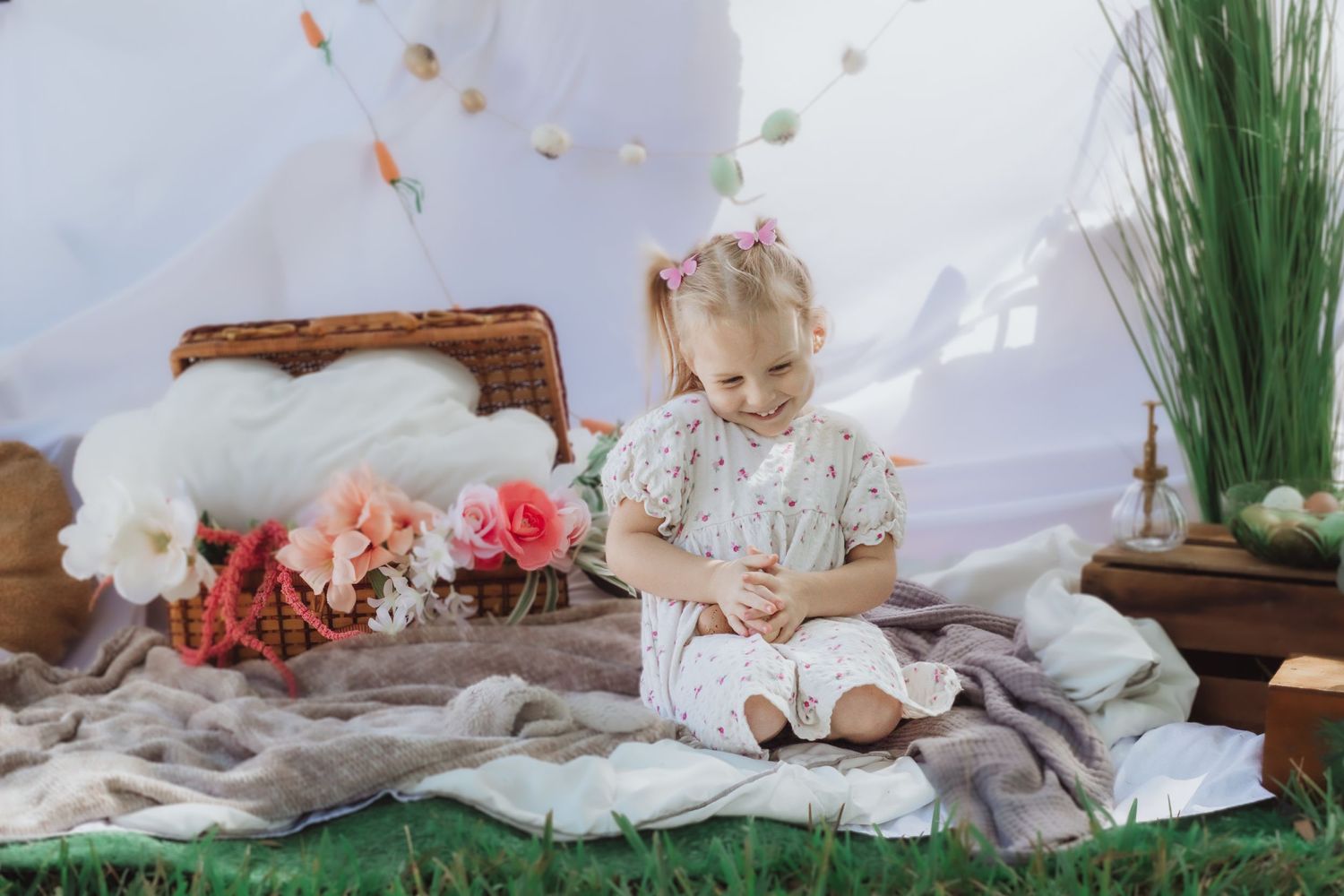 Child relaxing on white bedding with pink and coral flowers and boho decor accents.