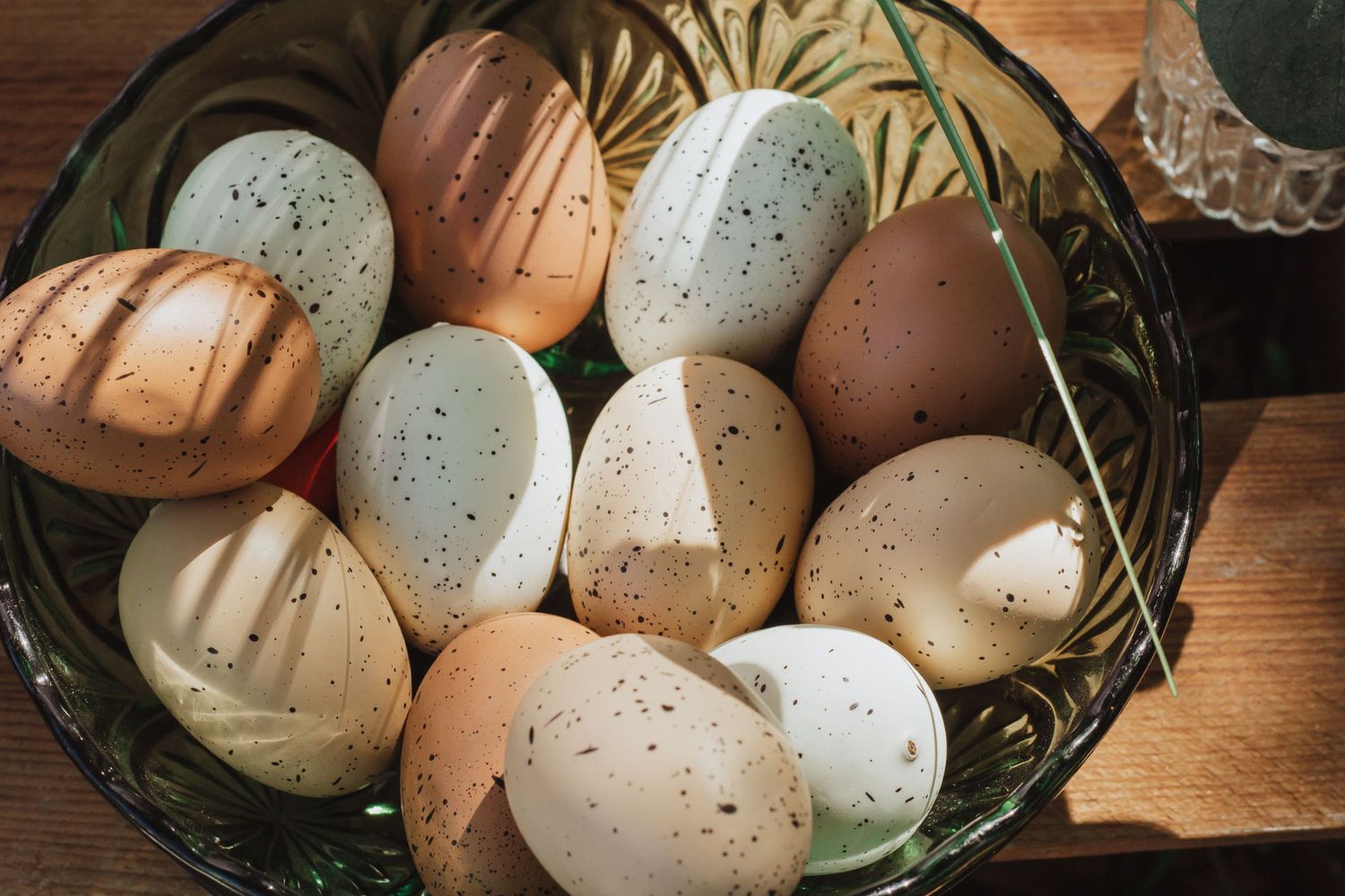 Farm fresh eggs in natural brown and speckled tones rest in a rustic wooden basket.