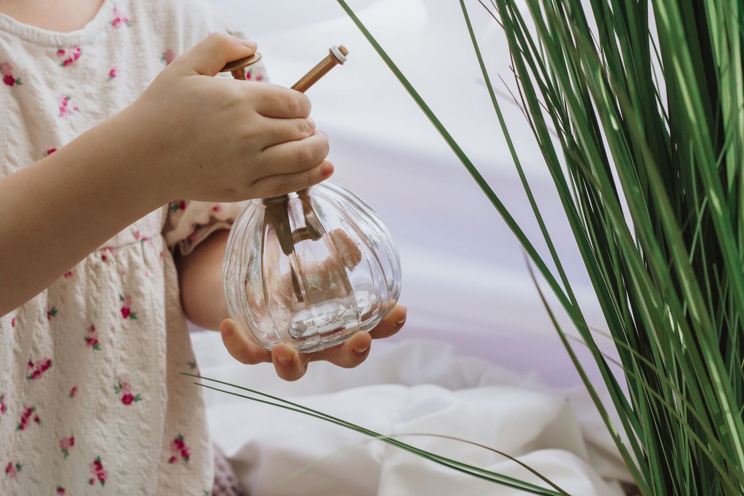 Hands reaching for decorative glass elements among tall green grass.