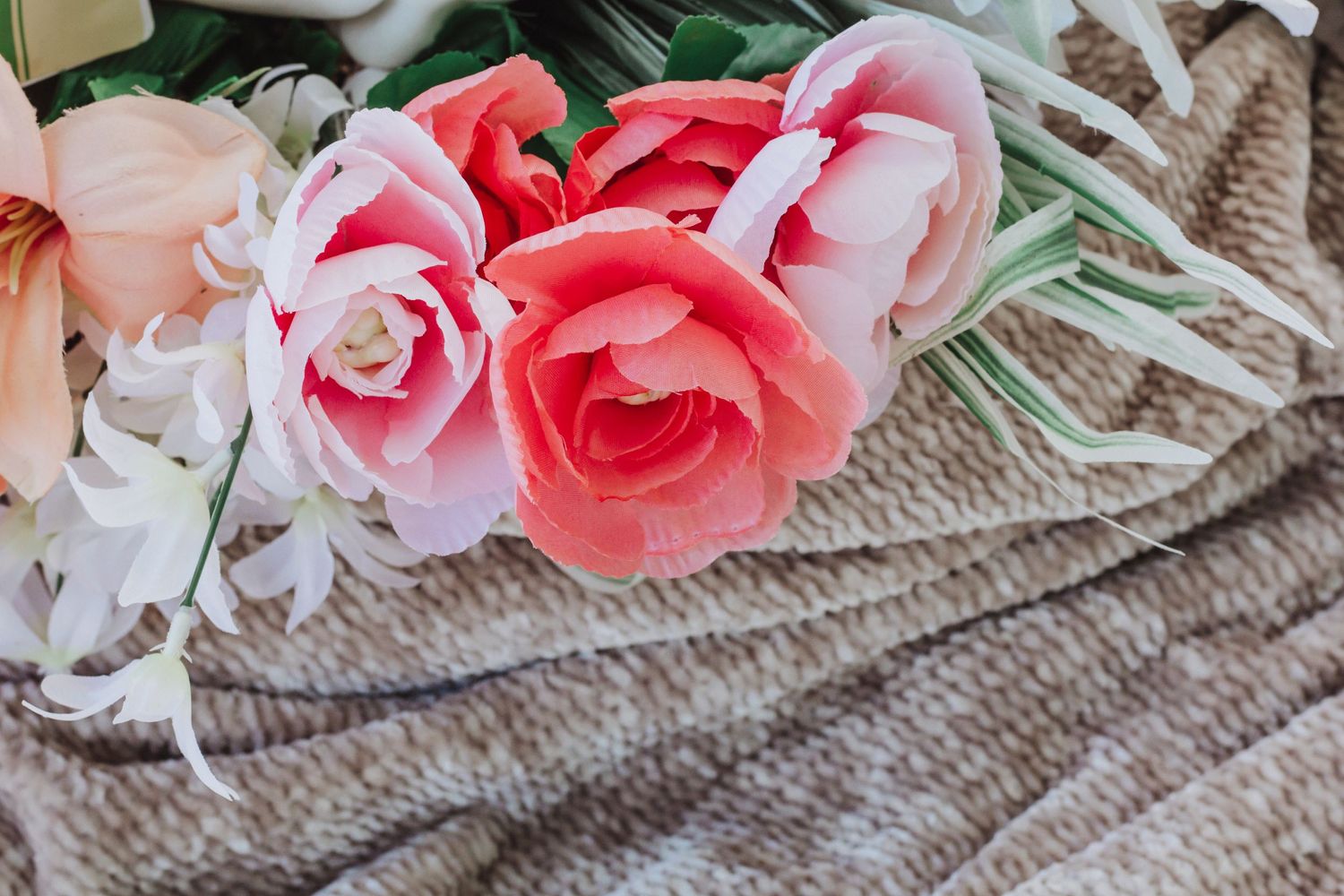 Pink roses and delicate lace create a romantic floral arrangement against a neutral background.