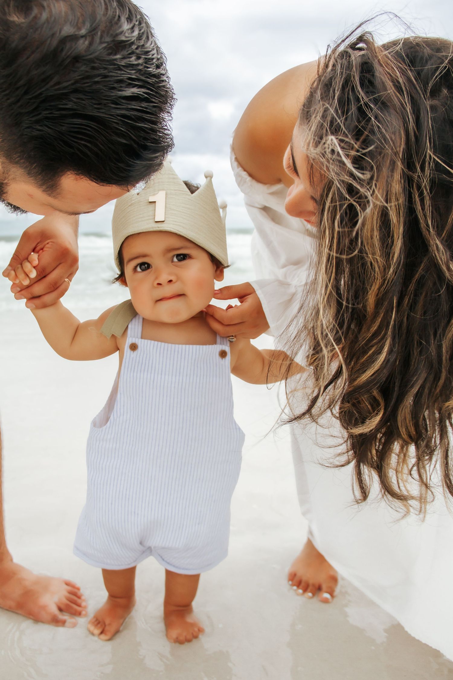 A series of beach photos showing small feet and a white romper outfit against sandy backgrounds from different angles.