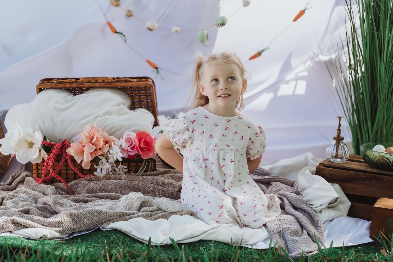 Sweet portrait of small child lying on white linens with decorative floral arrangements and hanging ornaments.