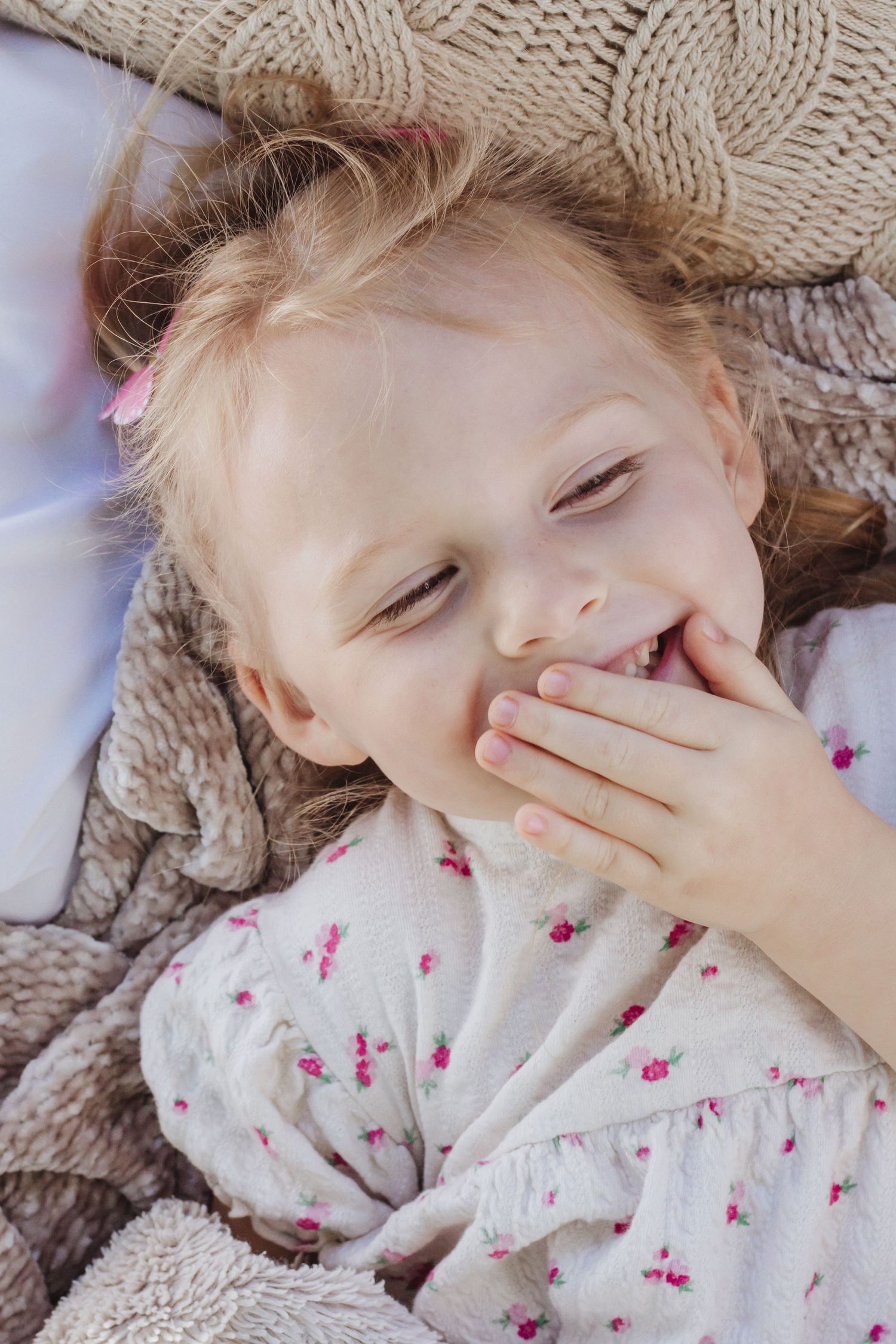 Playful portrait series showing expressions while lying on cozy knit blanket.