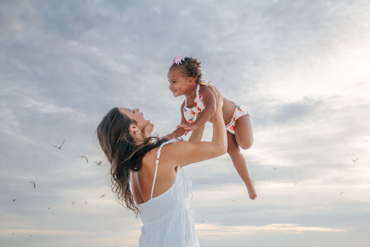 A sequence of joyful moments captured in silhouette against a cloudy sunset sky.