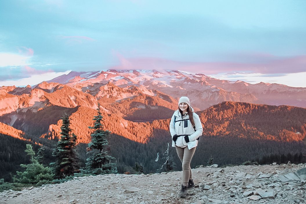 Snow-capped mountain peaks glow orange during sunset against a vibrant blue sky.