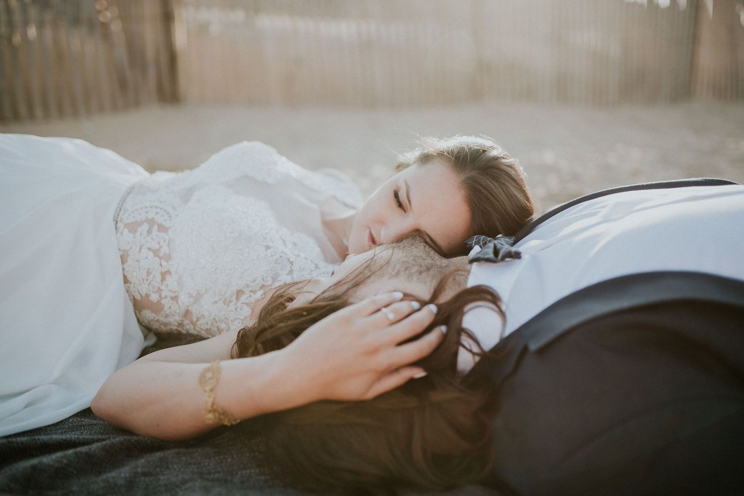 Someone lying down peacefully on a bed wearing a white lace dress in soft, dreamy lighting.