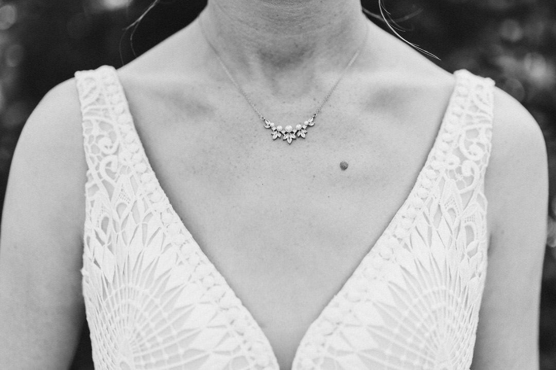 Detail shot of bridal gown featuring embroidered V-neckline and delicate jewelry.