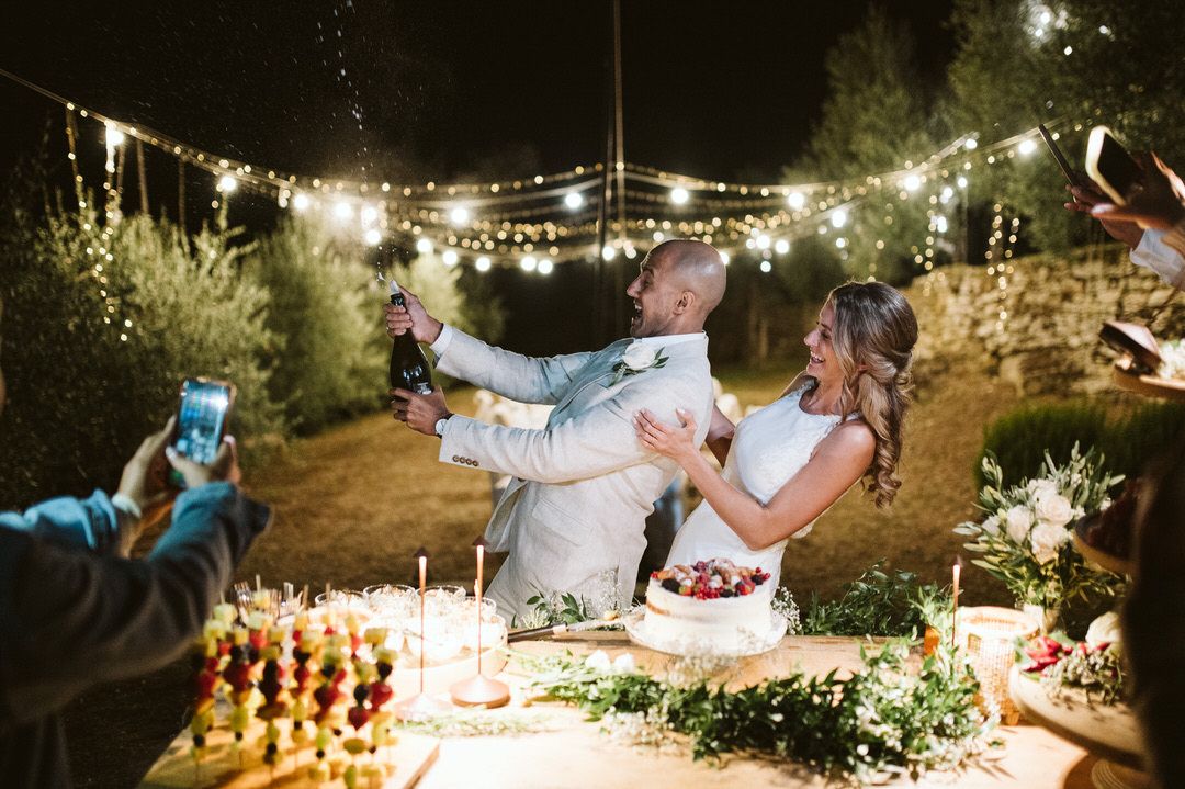 Wedding celebration at night with string lights and cake cutting ceremony.