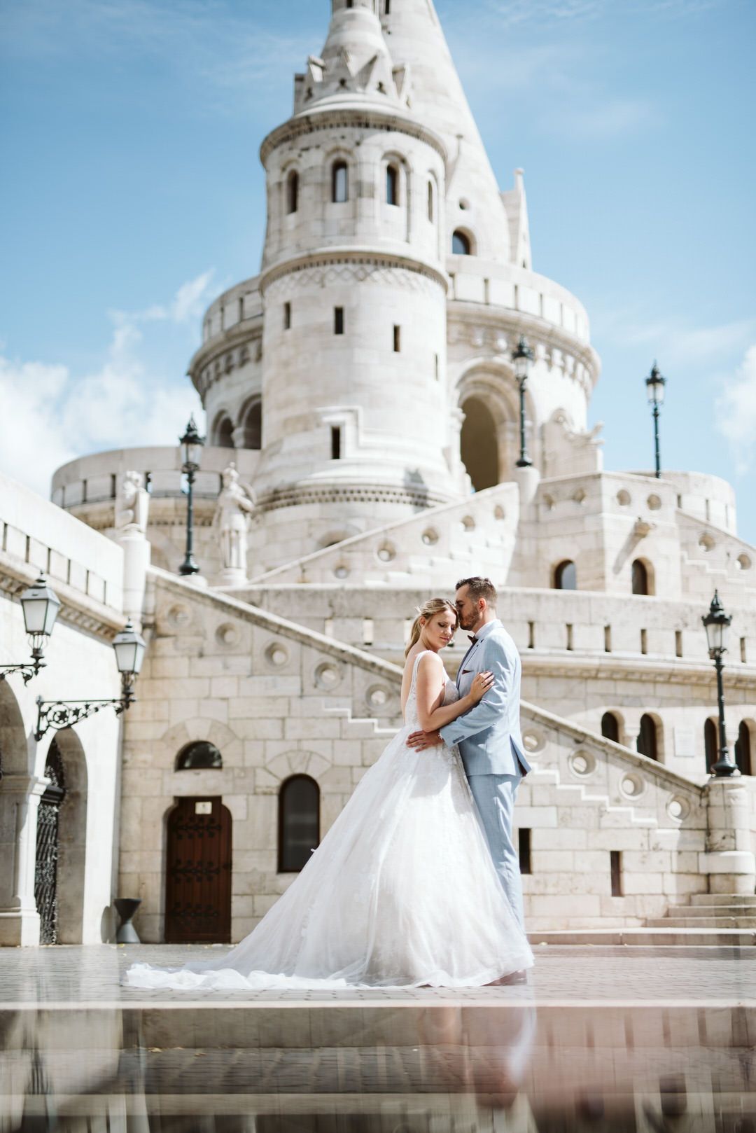 A white wedding dress couple poses in front of the iconic Fisherman's Bastion castle in Budapest, Hungary.