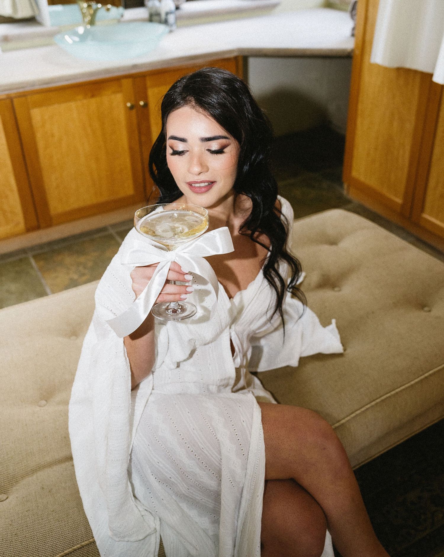 A person in a white robe relaxes with a drink in an elegant interior setting.