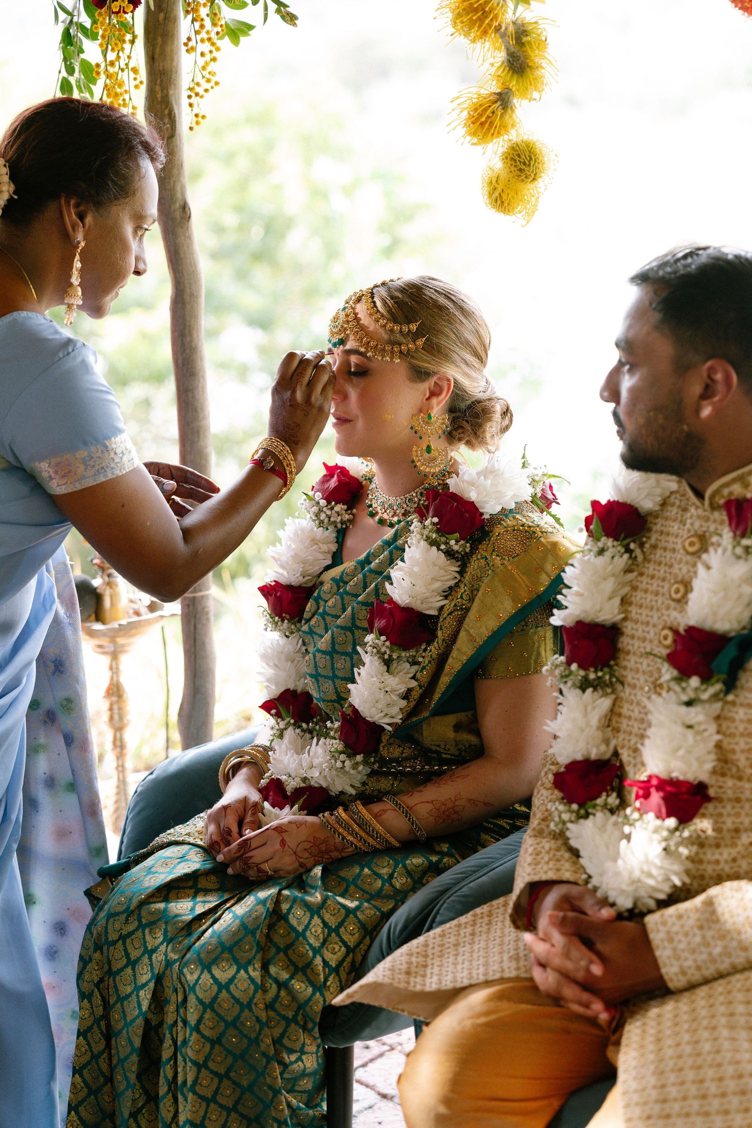 A traditional Indian fusion wedding ceremony with decorative flower garlands and cultural attire taking place outdoors.