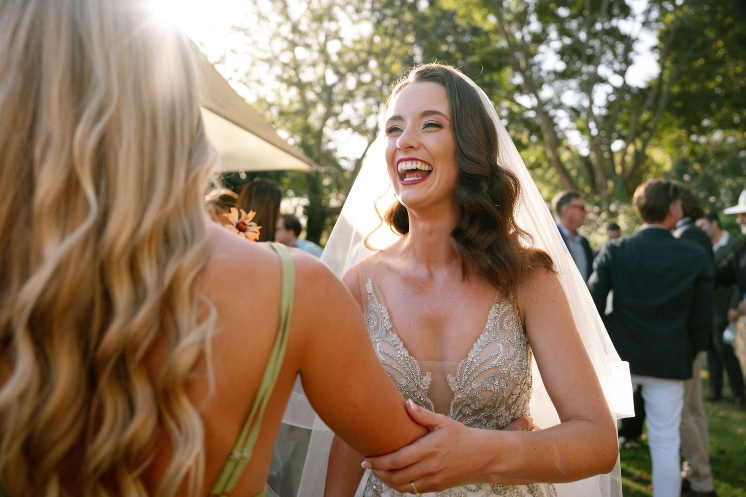 A joyful moment captured between wedding guests at an outdoor celebration.