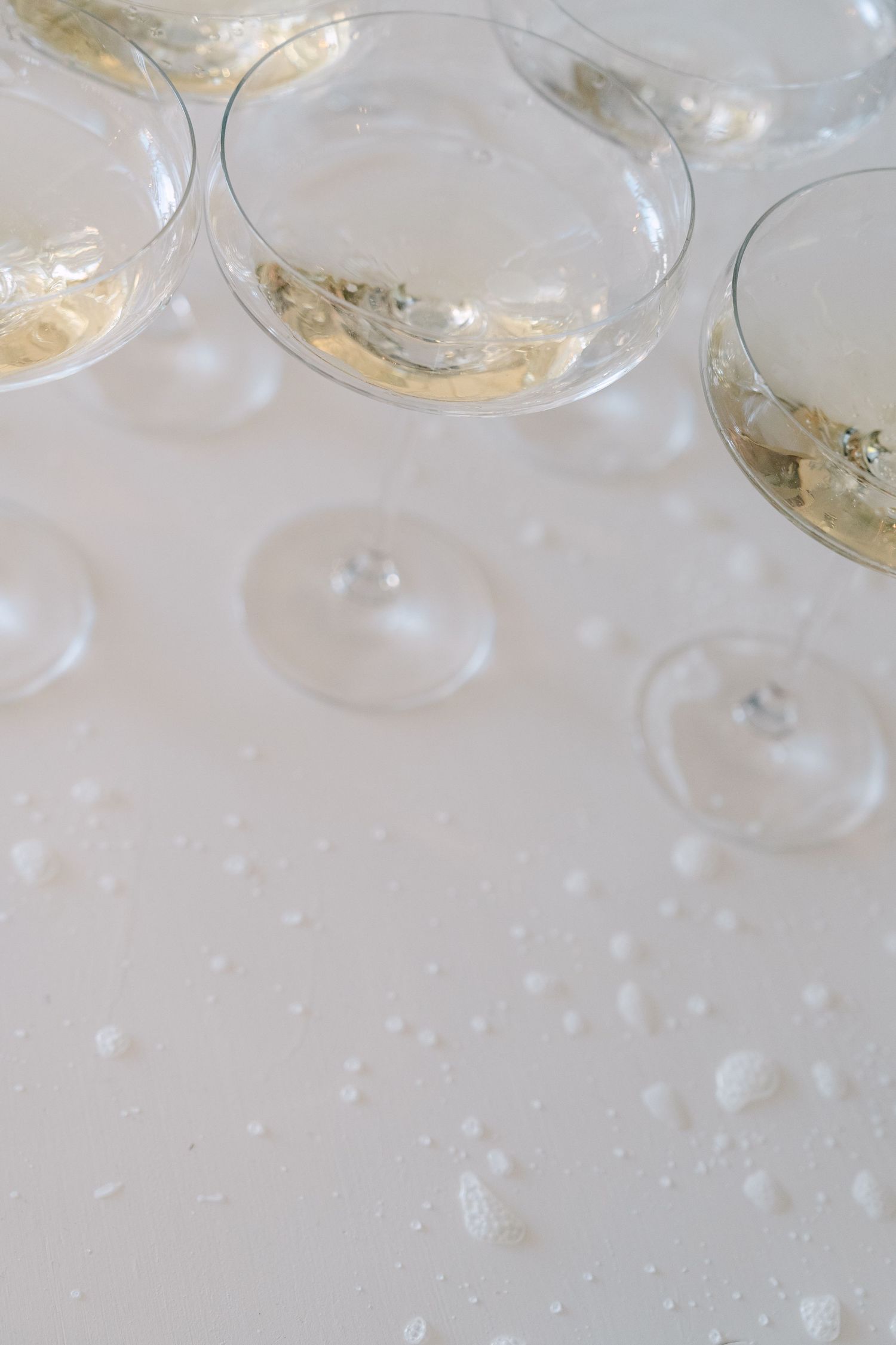 Empty champagne glasses on a white surface with delicate drops of residual liquid creating an elegant atmosphere.
