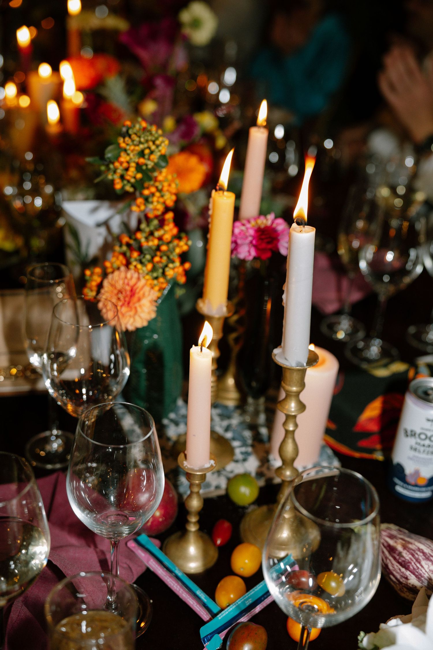 Festive table setting with lit candles, wine glasses, and colorful autumn floral arrangements.