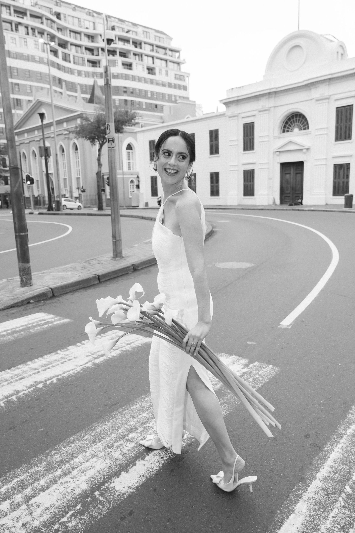A sequence of black and white photos showing a person in a white dress walking on a curved street.
