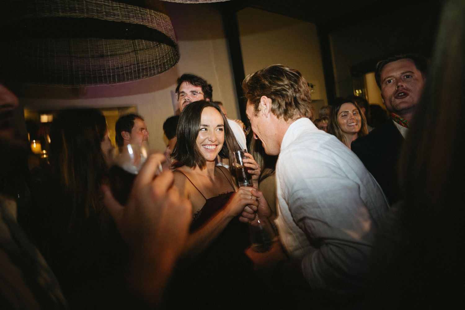 Lively party scene with people dancing and celebrating under warm lighting.
