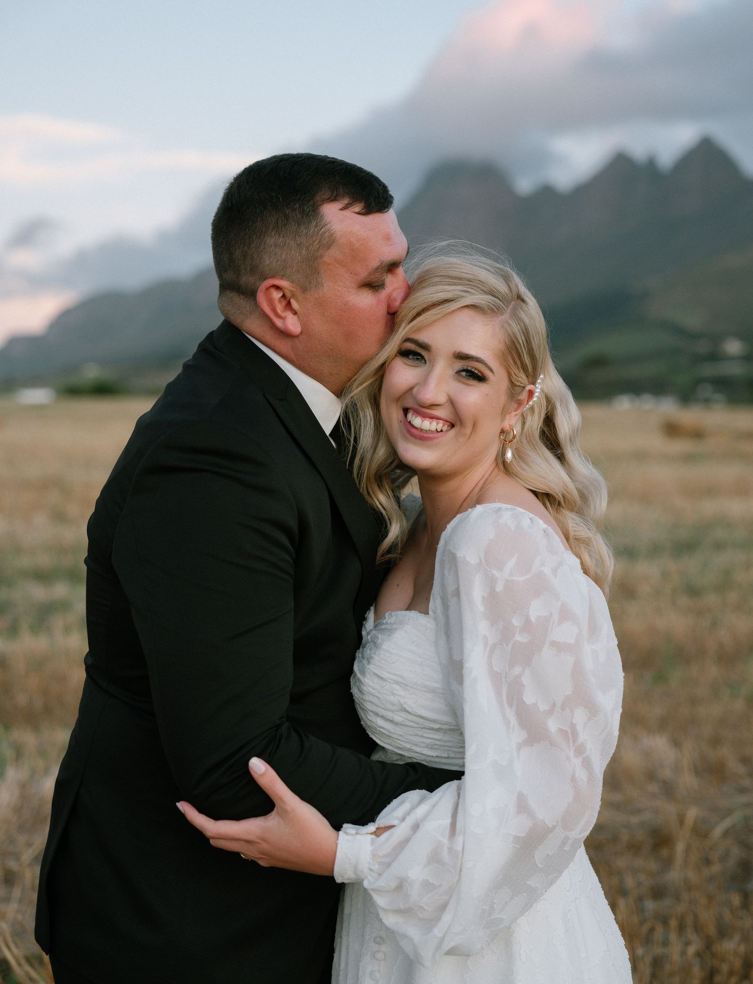 A joyful wedding moment captured against a mountain backdrop at sunset.