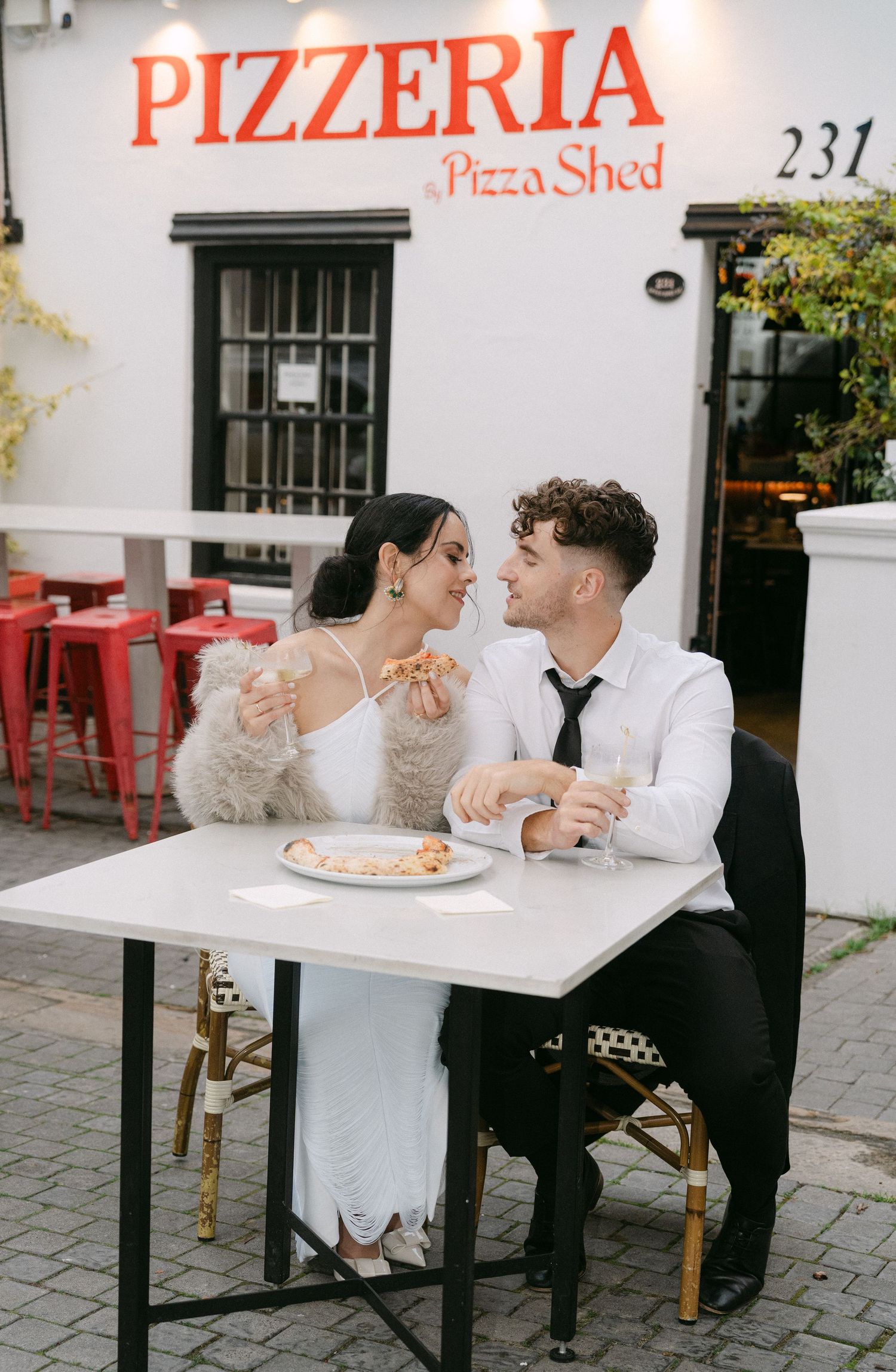A romantic couple shares pizza at an outdoor pizzeria table in a series of candid black and white photographs.