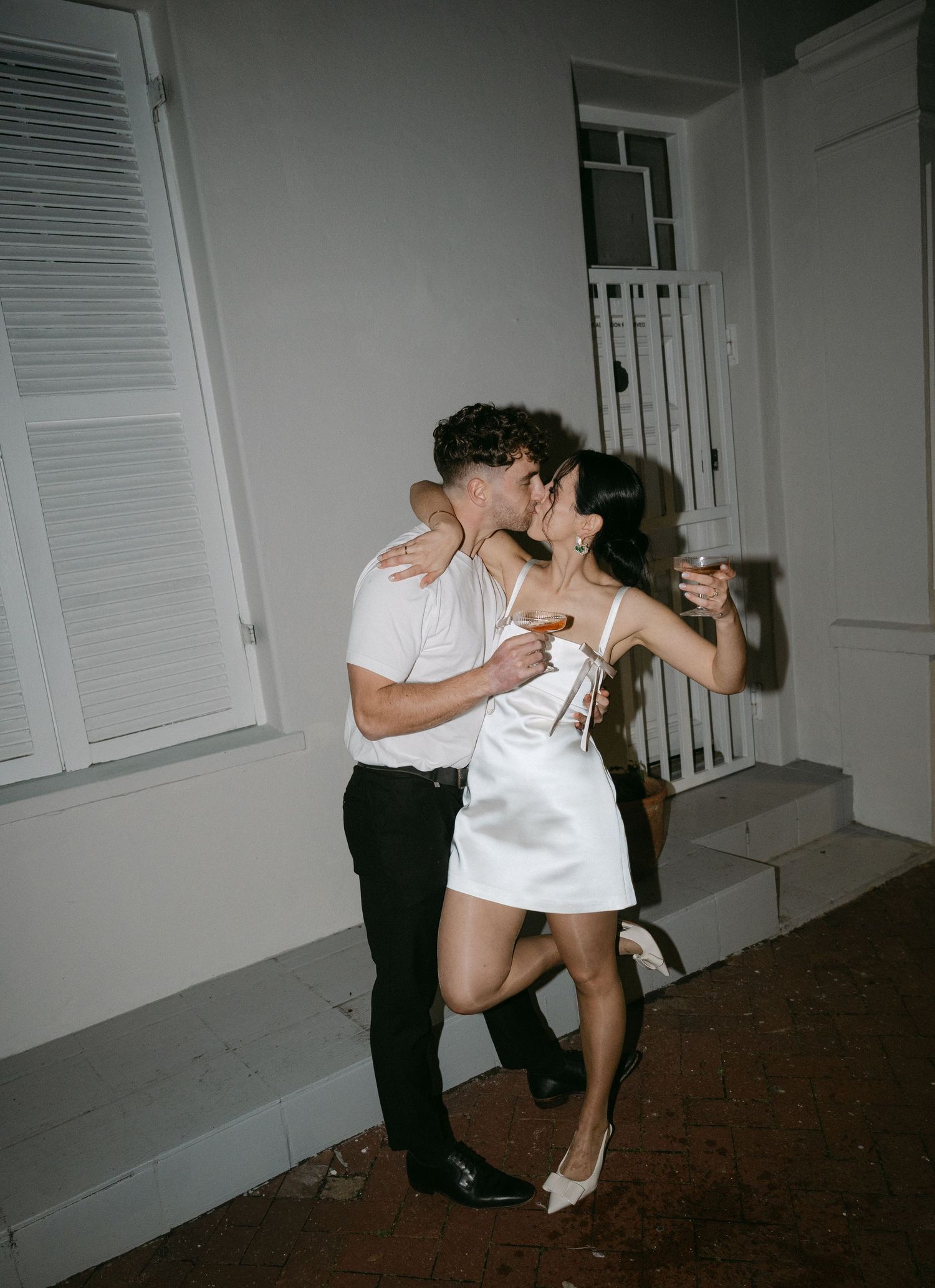A romantic dance sequence captured in black and white shows a couple in intimate poses against a wall.