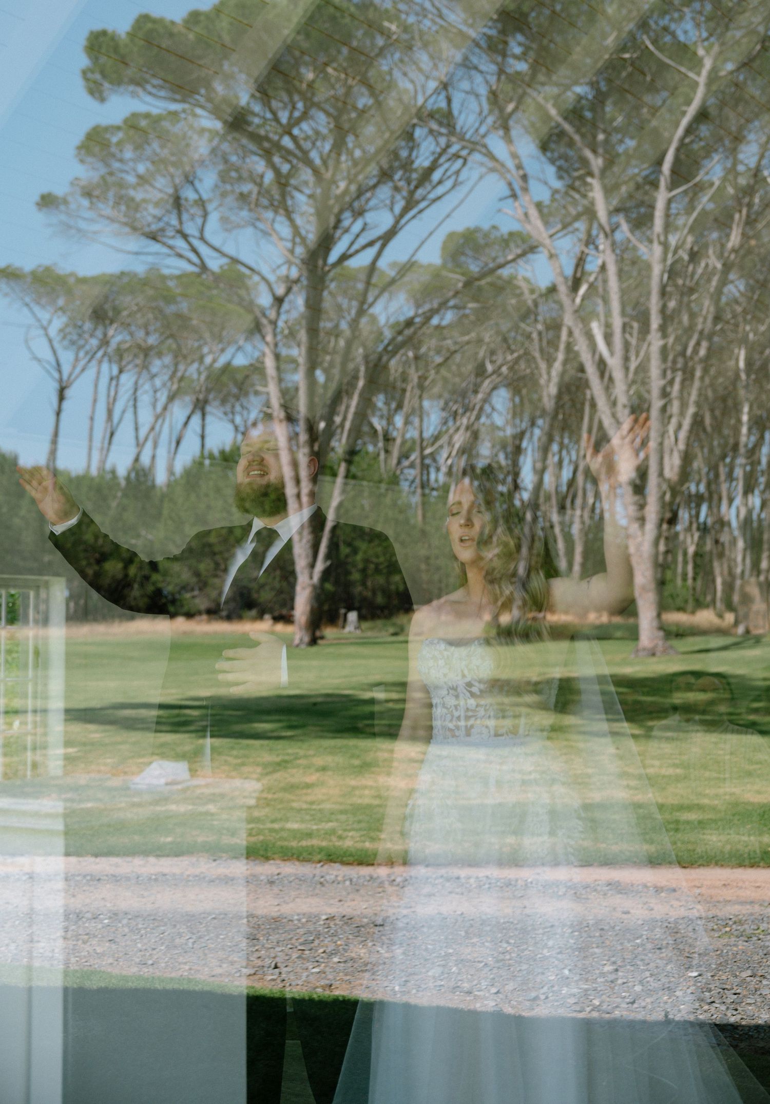Double exposure photo of wedding couple against trees in sunlit park.