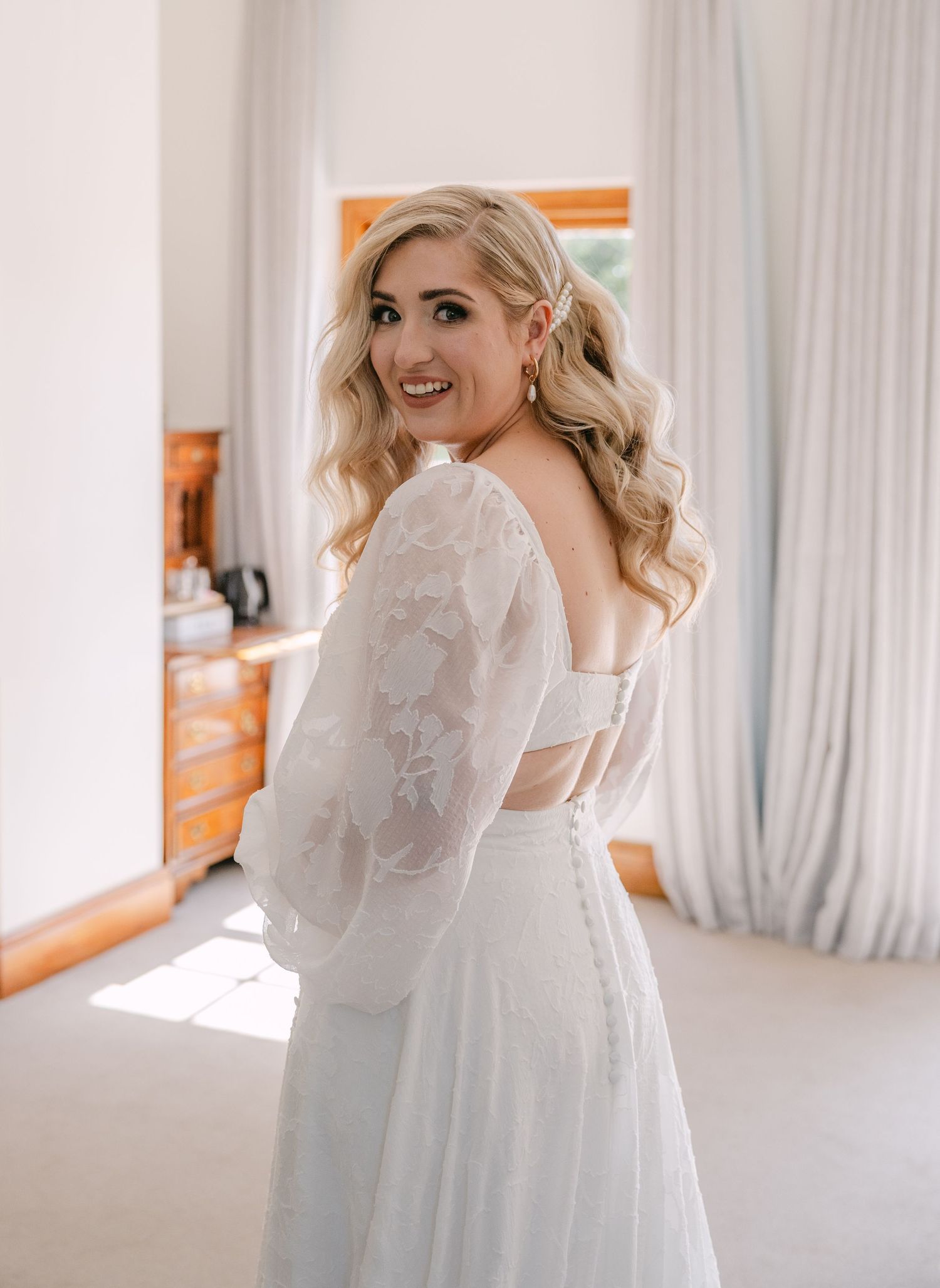 Wedding dress with delicate lace sleeves and open back detail.