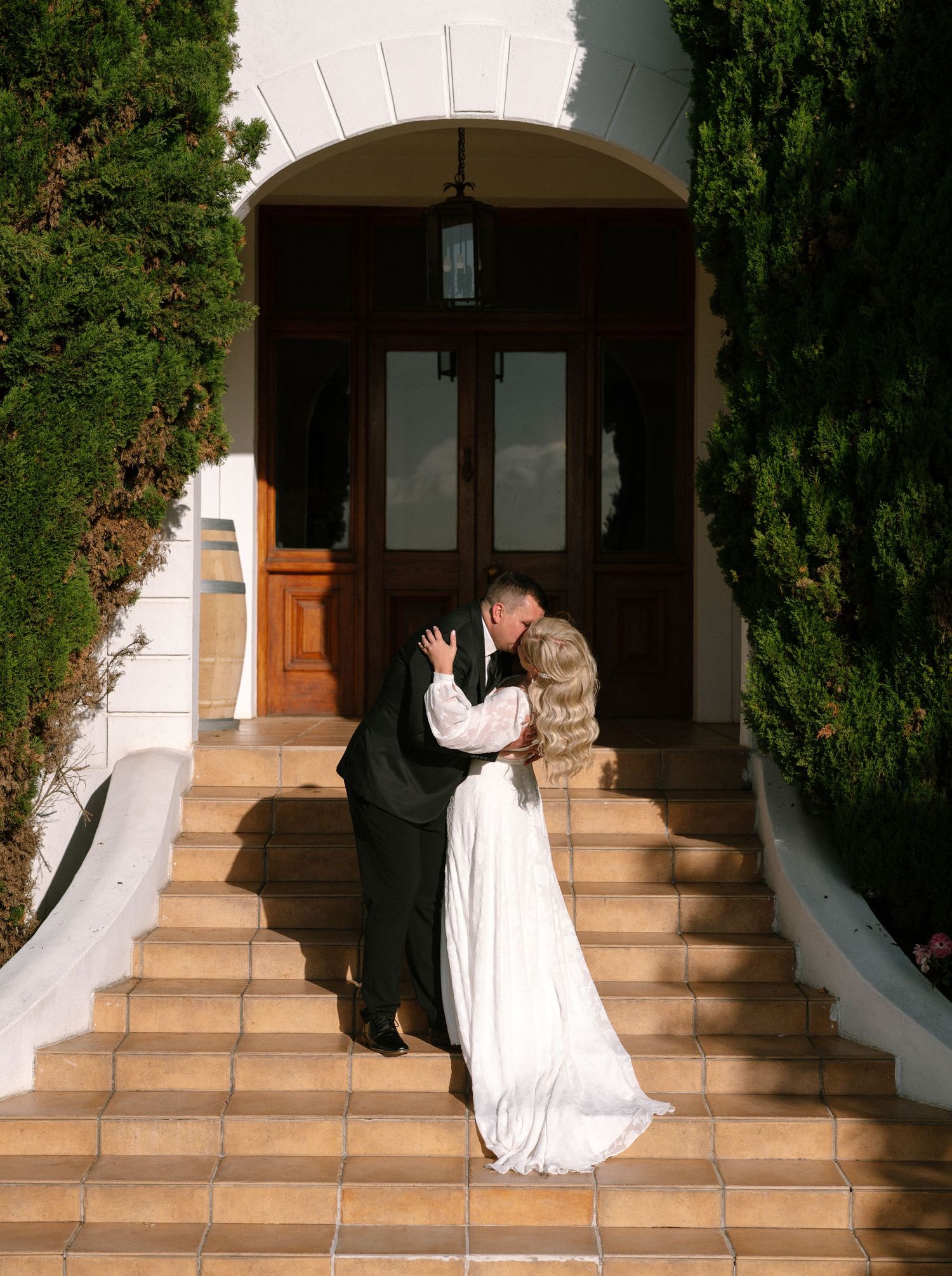 A couple sharing a tender moment on stone steps leading to an arched doorway.