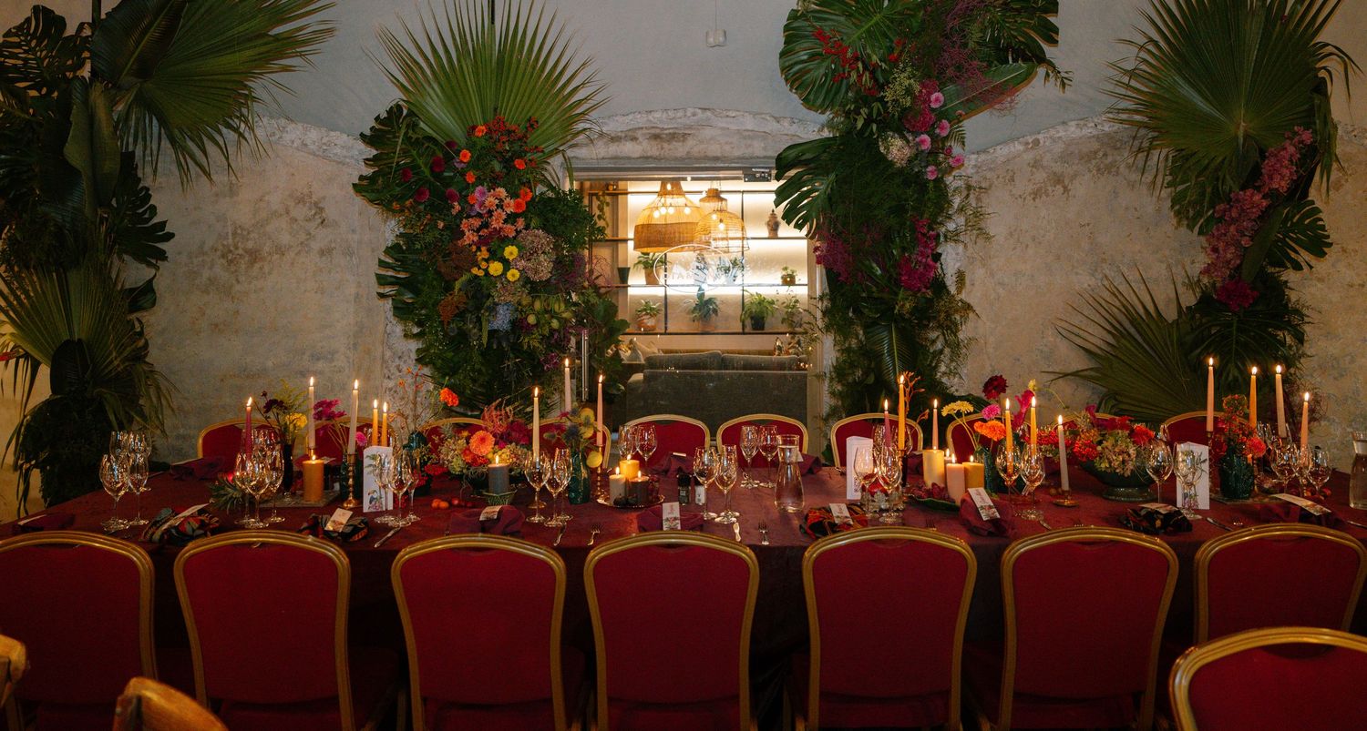Elegant wedding reception table decorated with tropical greenery and warm candlelight.