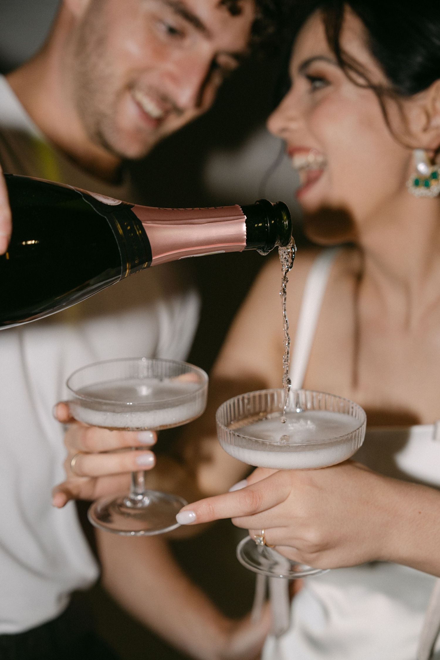 Champagne being poured into vintage coupe glasses during an elegant celebration.