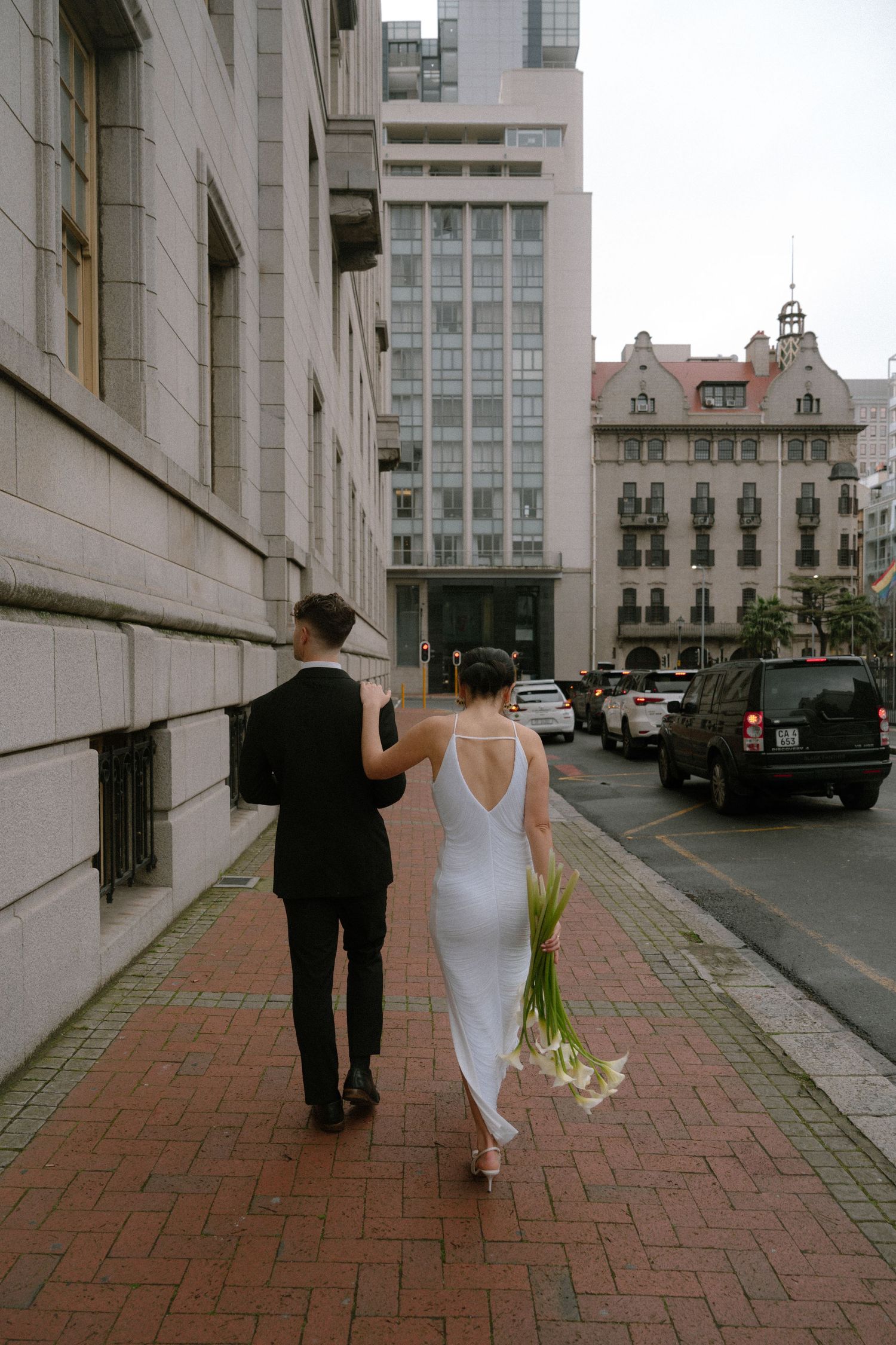 A sequence of four photos showing two people walking down a brick-paved urban street between buildings.