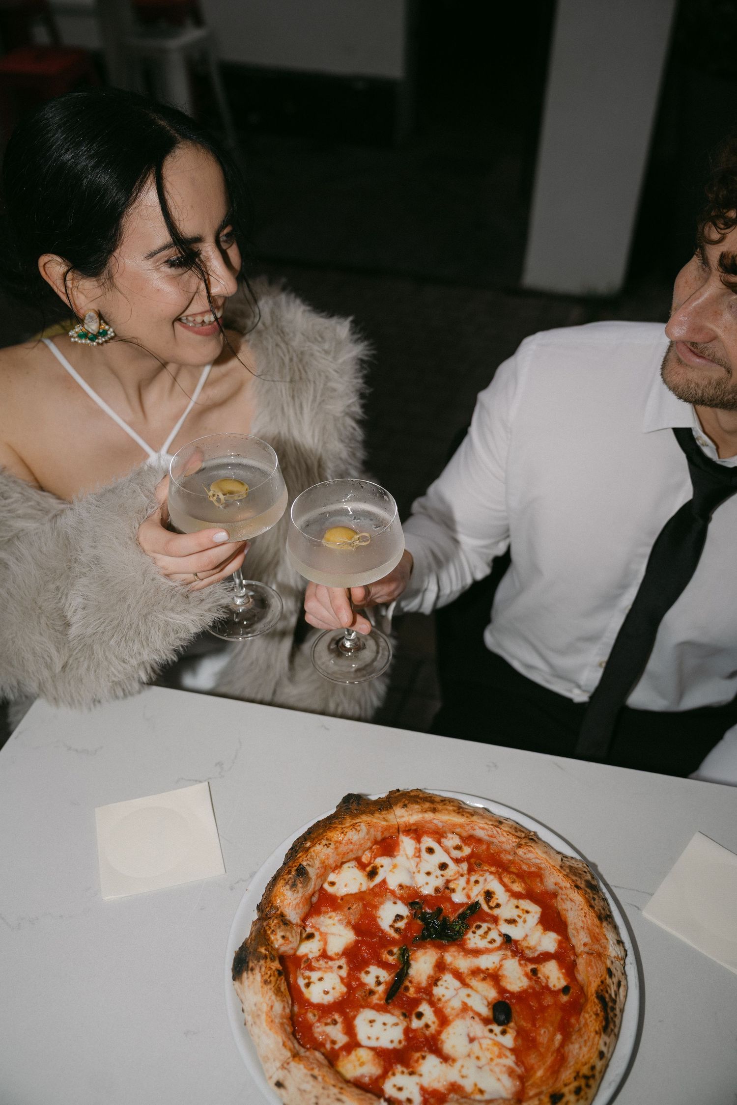A series of photos showing a Neapolitan pizza being served and enjoyed at a restaurant table.
