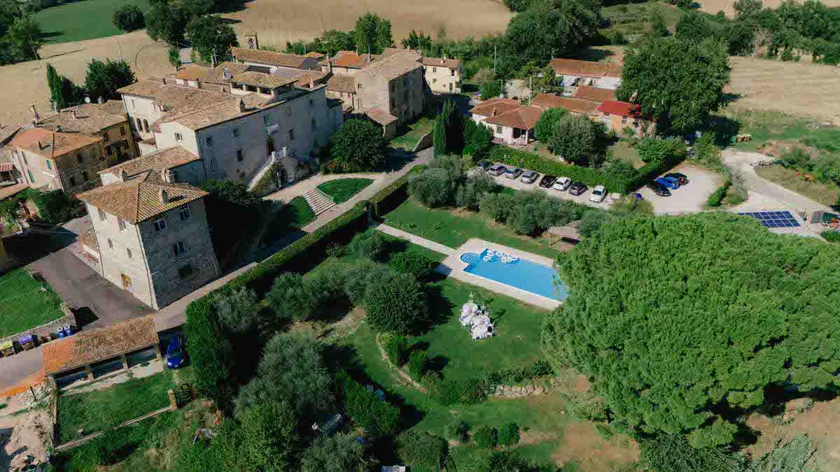 Aerial view of Italian villa with swimming pool surrounded by lush greenery.