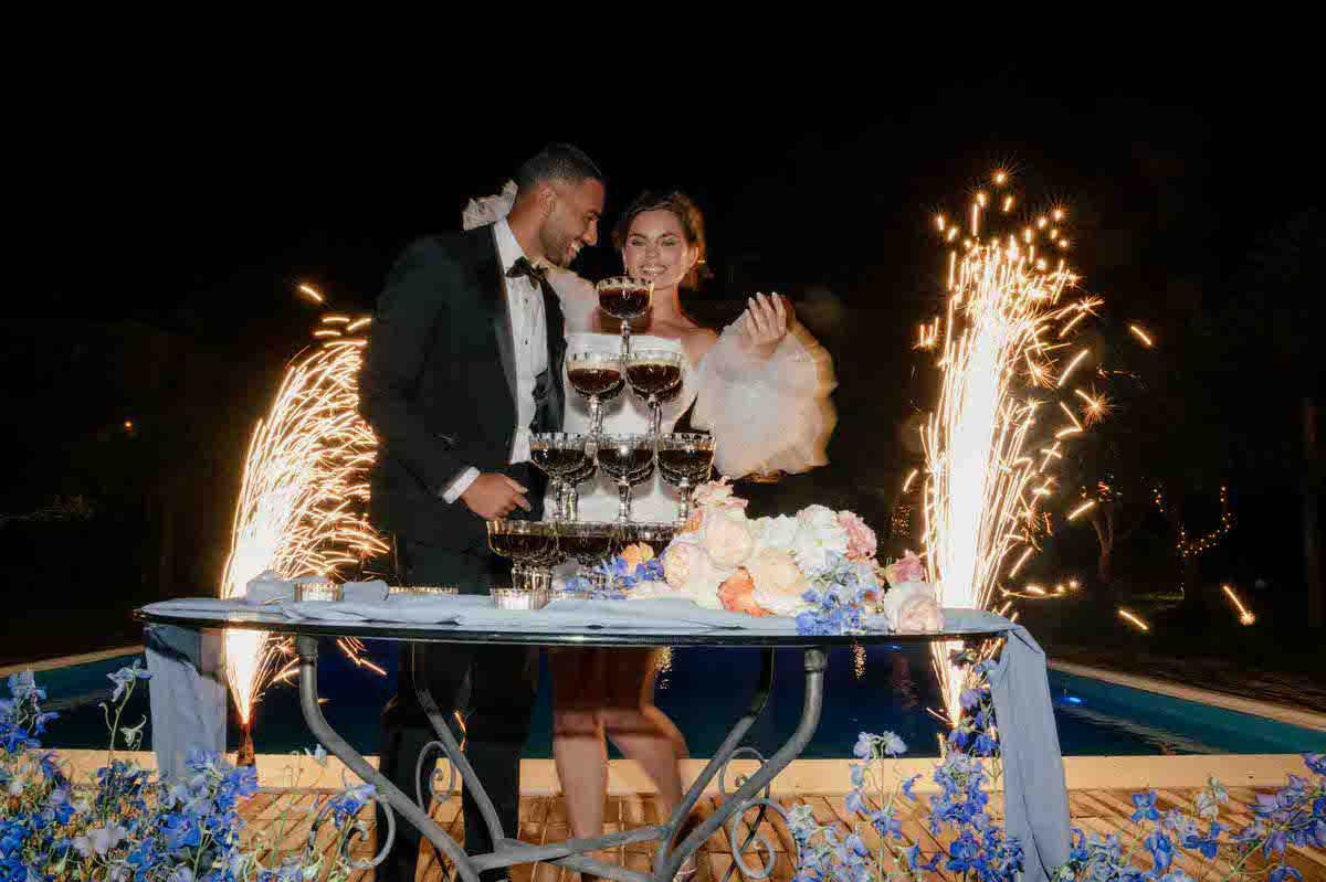 Newlyweds cutting wedding cake with sparkler fountains creating dramatic effect.