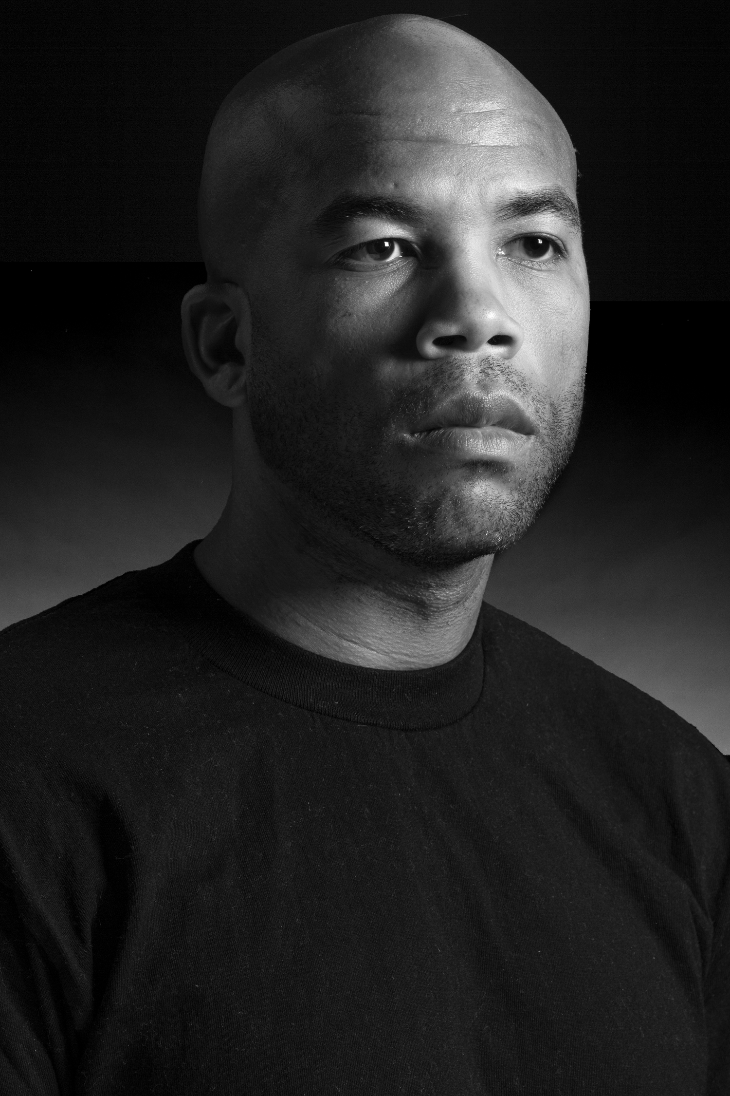 Dramatic black and white portrait with moody lighting against dark background.