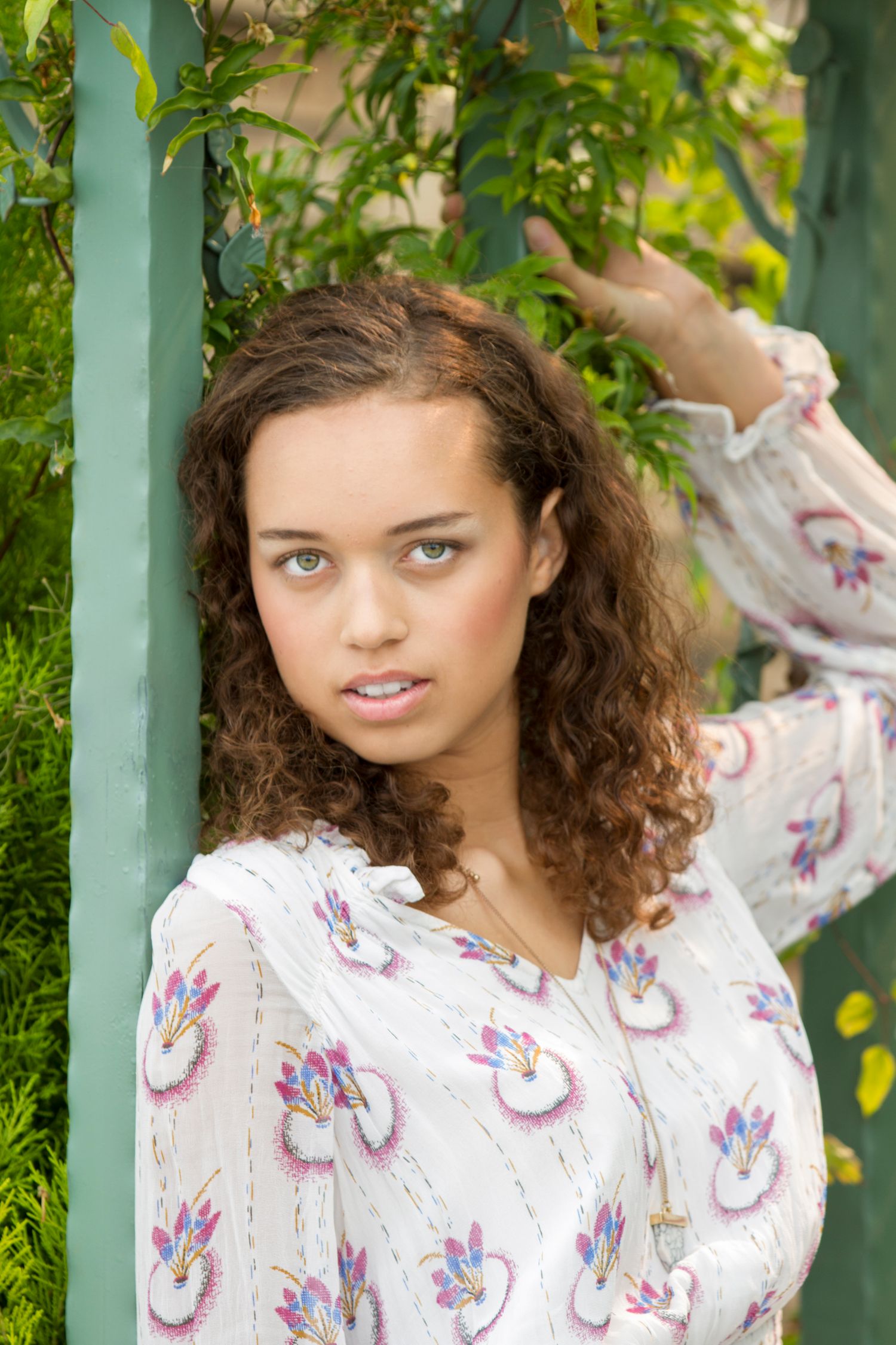 Portrait series against a green garden trellis backdrop with natural lighting.