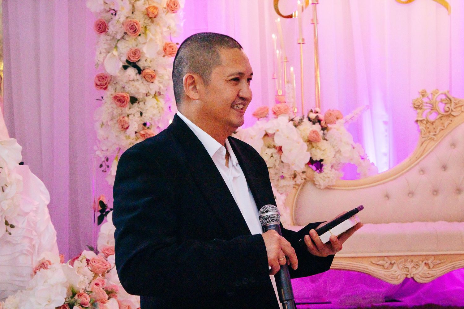 Wedding reception venue decorated with pink floral arrangements and elegant lighting.