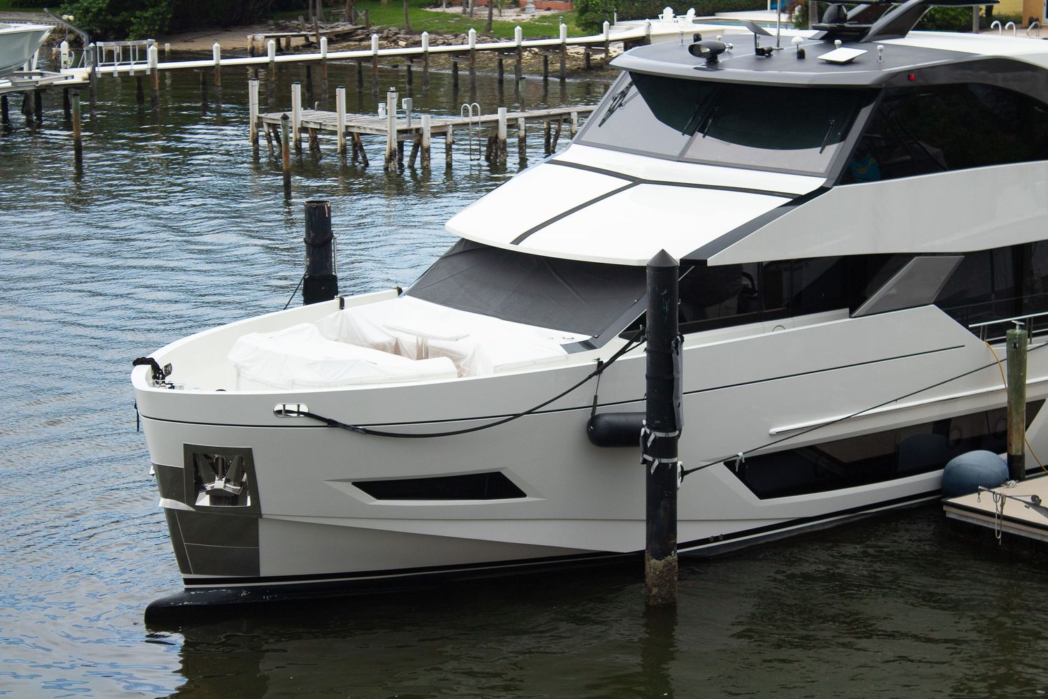 Modern luxury yacht with sleek black and white design moored at wooden dock in marina.