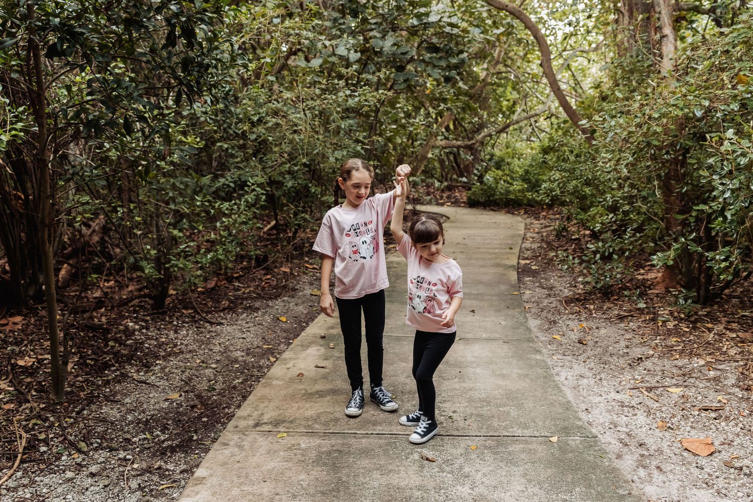 People walking on a nature trail through lush green forest on a sunny day.
