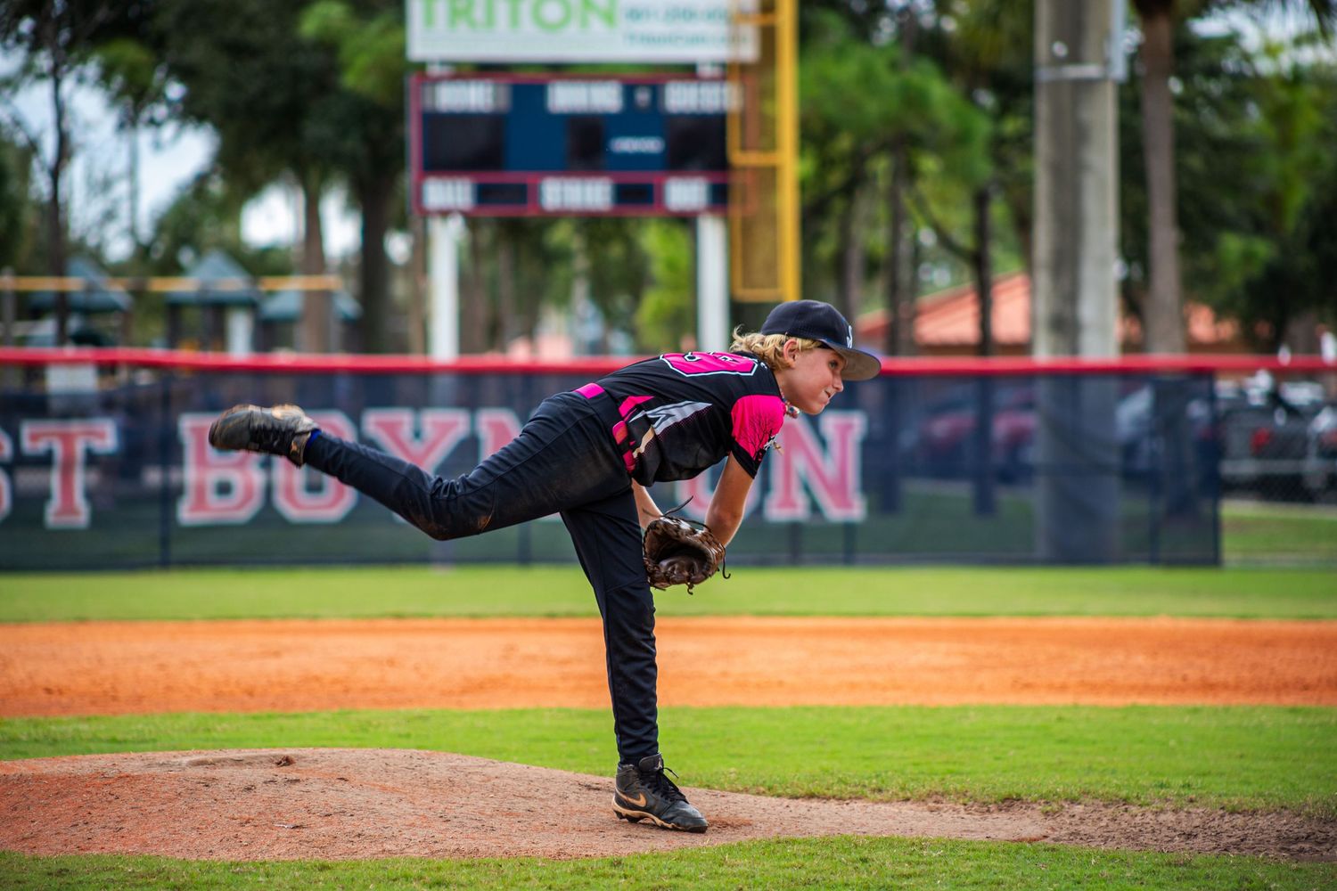 A pitcher follows through on their delivery motion on a dirt baseball mound during a game.