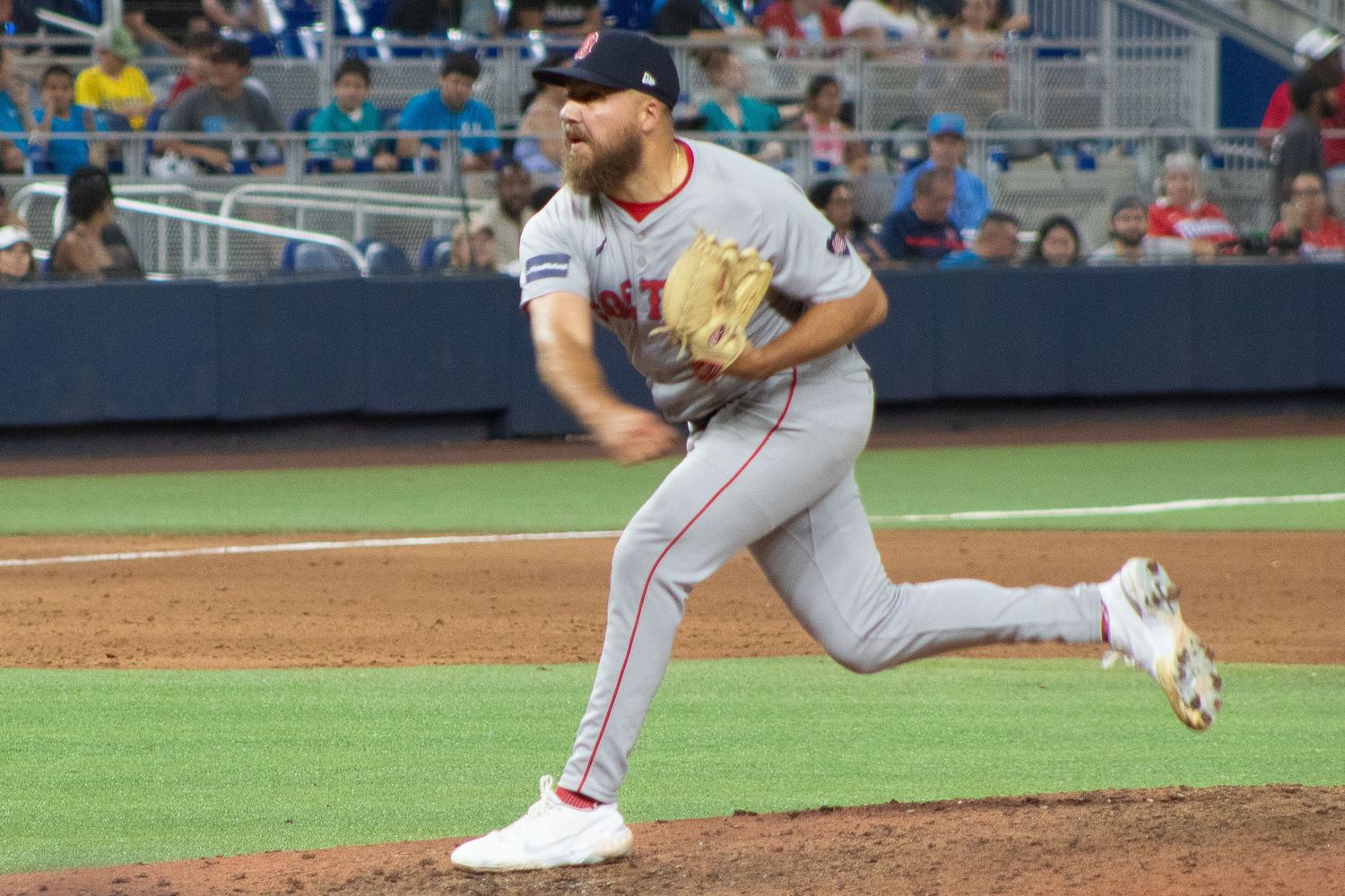 Baseball pitcher follows through on delivery during night game.
