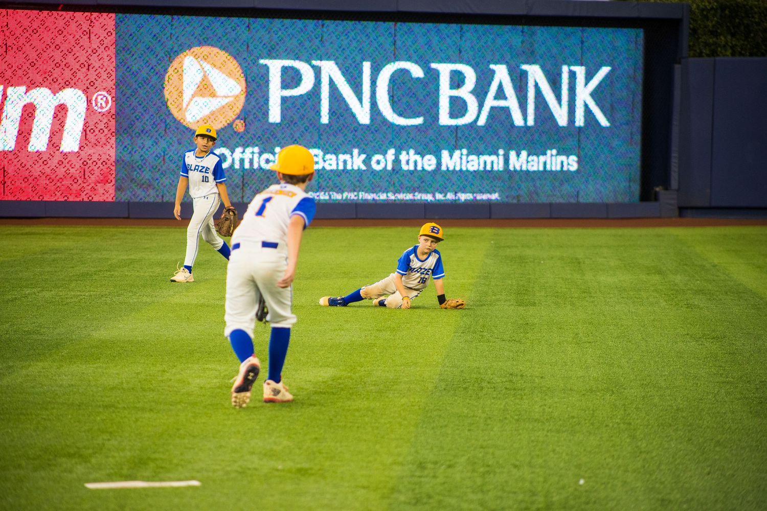 Baseball players practicing on field with PNC Bank advertisement visible in background.