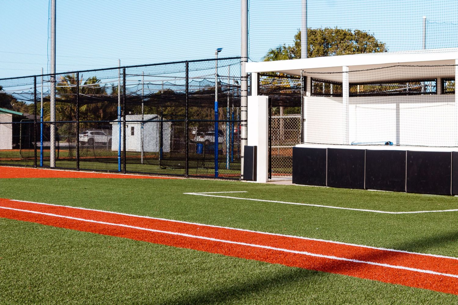 Baseball field with white structures and red foul lines visible.